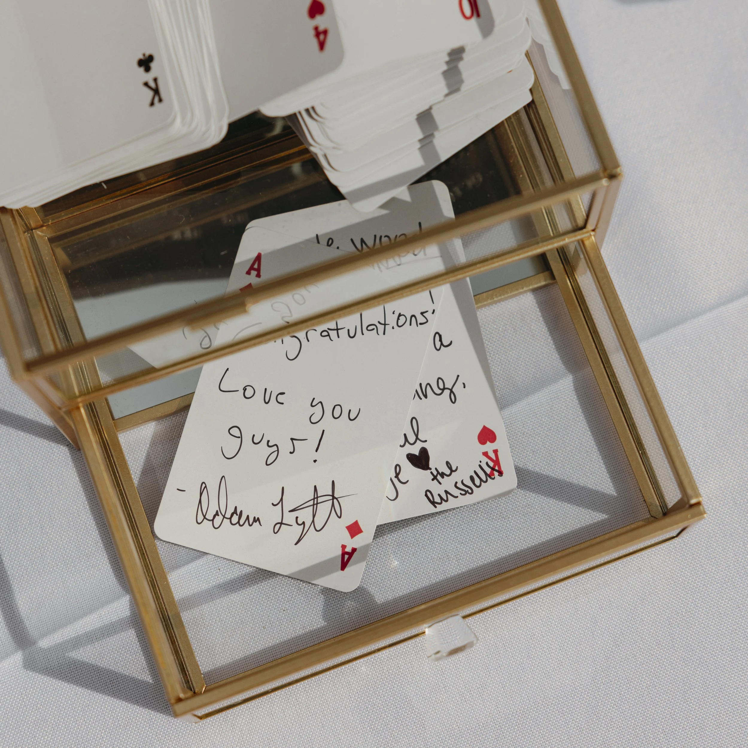 A glass box with a mirror inside, holding a handwritten note and a playing card, the Ace of Hearts.