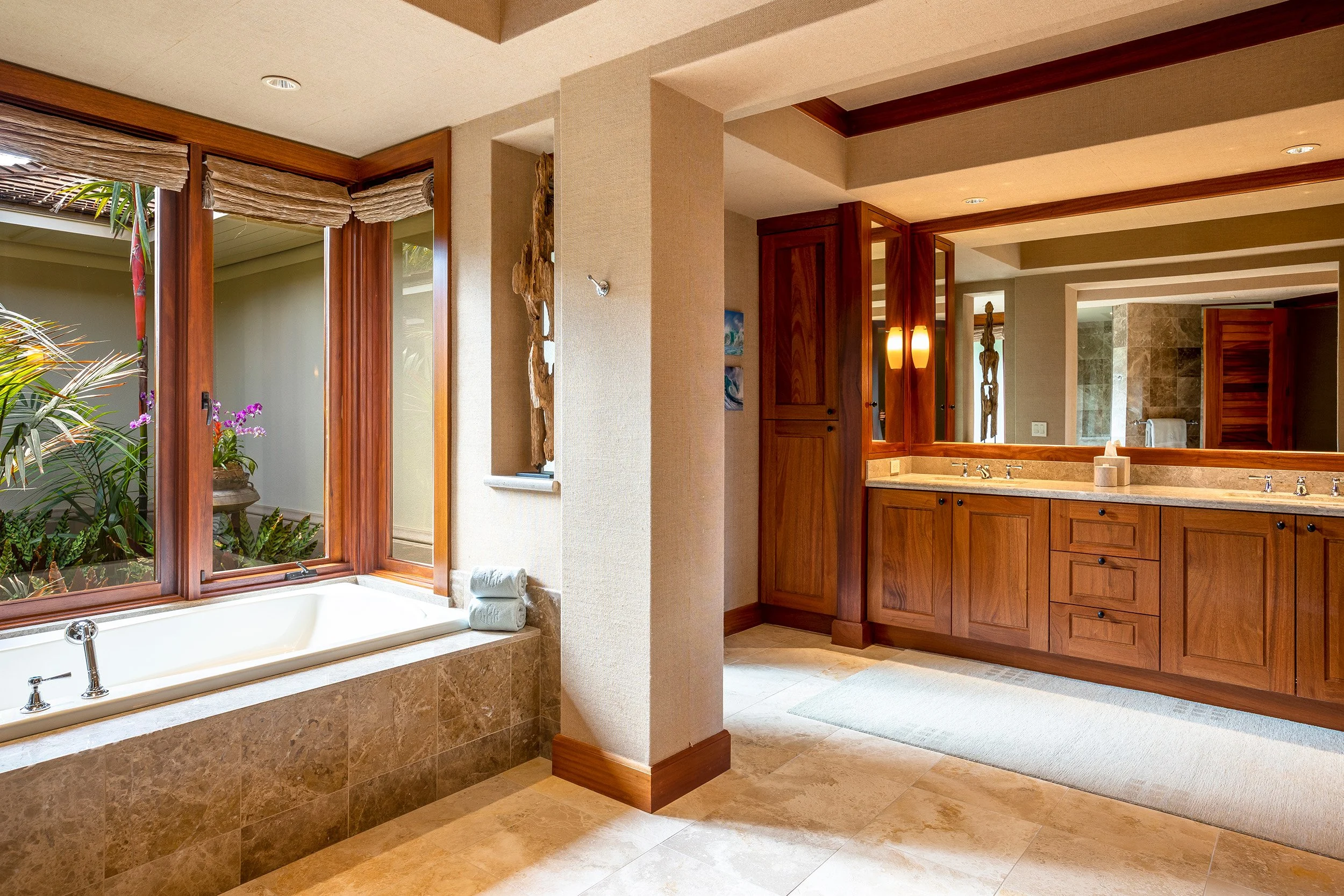 この豪華なプライマリバスルームには、デュアルバニティ、浸かり風呂、タイル張りのウォークインシャワーがあります。マホガニーキャビネット、大理石のカウンタートップ、ストーンフローリングが雰囲気を高めています。