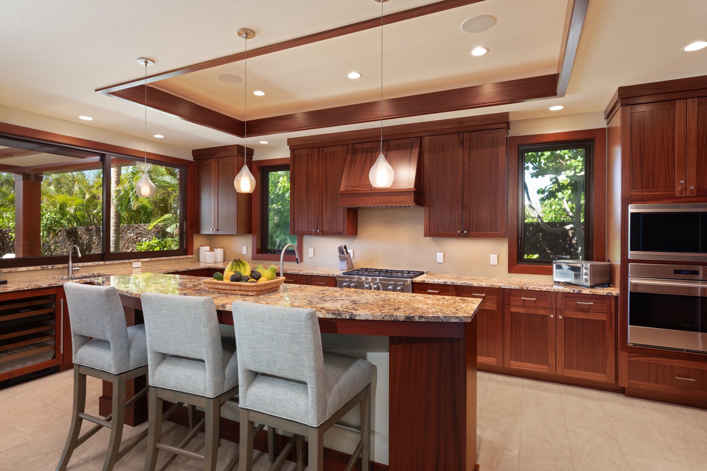 Large island with bar seating and a pass-through window that opens to the lanāi barbecue.