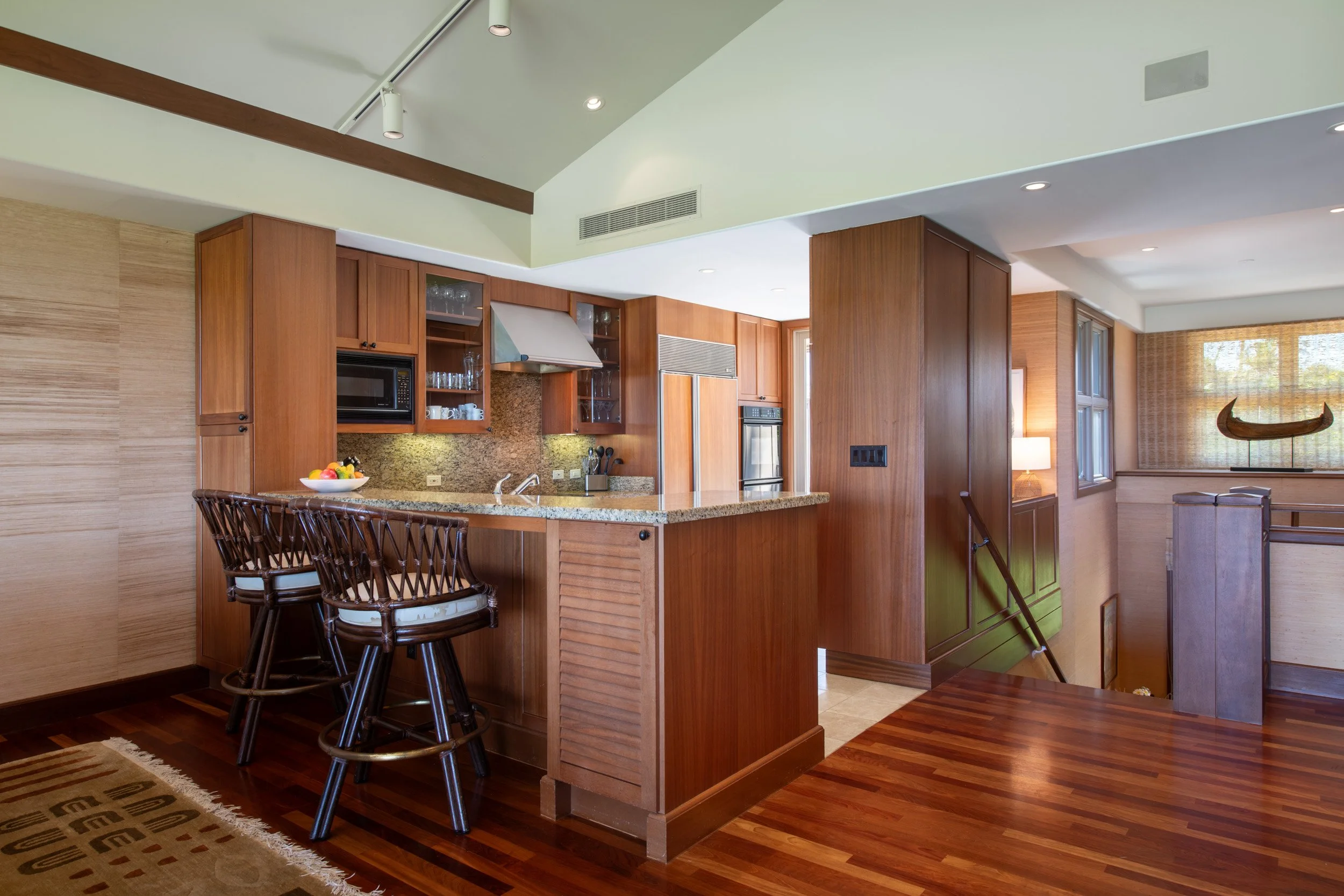 Well-designed kitchen includes stone countertops, a wrap-around bar, and mahogany cabinets. 
