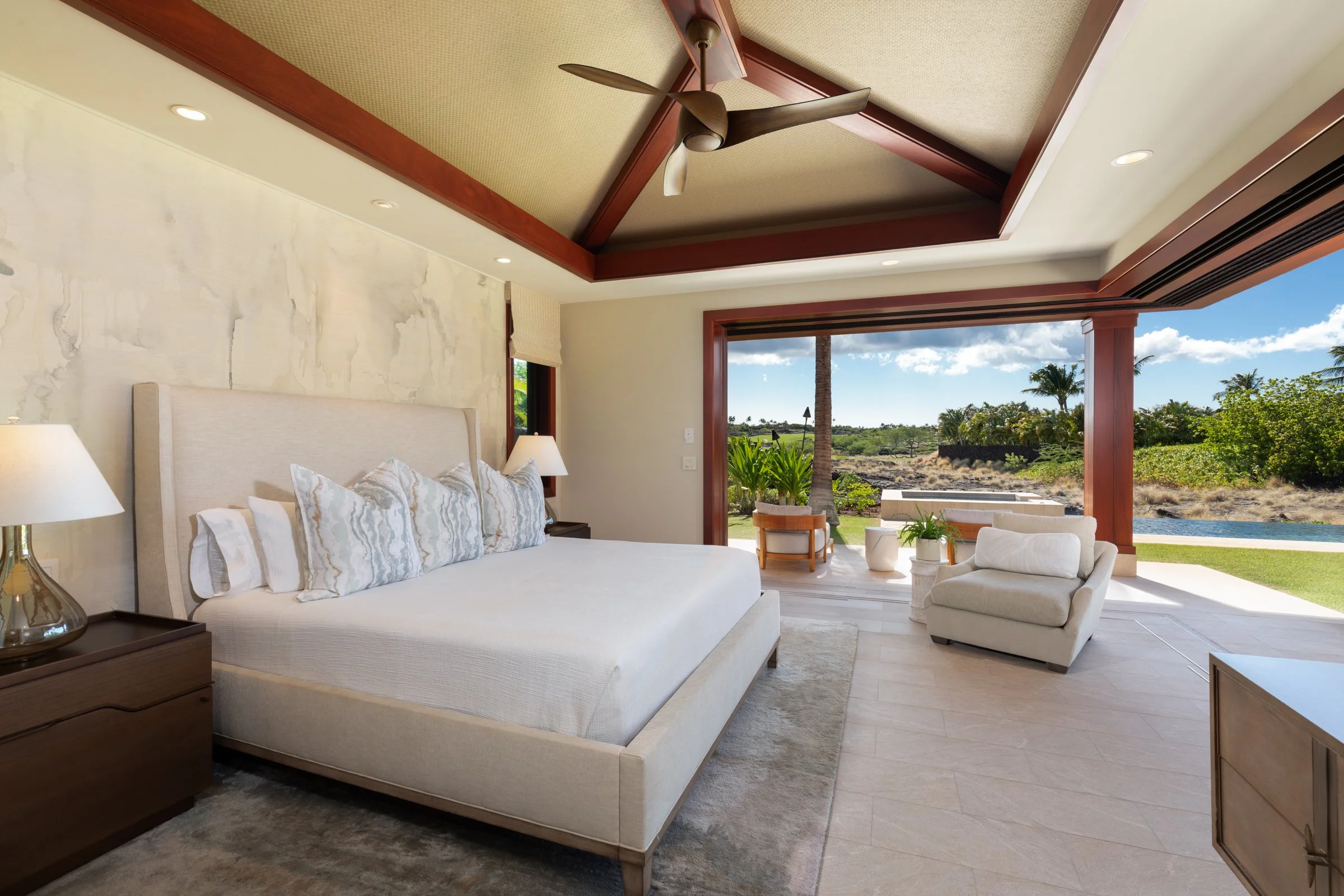 Primary bedroom with vaulted ceilings expands onto the covered lanāi with streamlined corner-less pocketing doors.