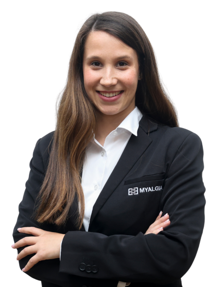 Mulher jovem sorridente com cabelo castanho, usando traje formal preto e camisa branca, com logotipo da MYALGIA, cruzando os braços.