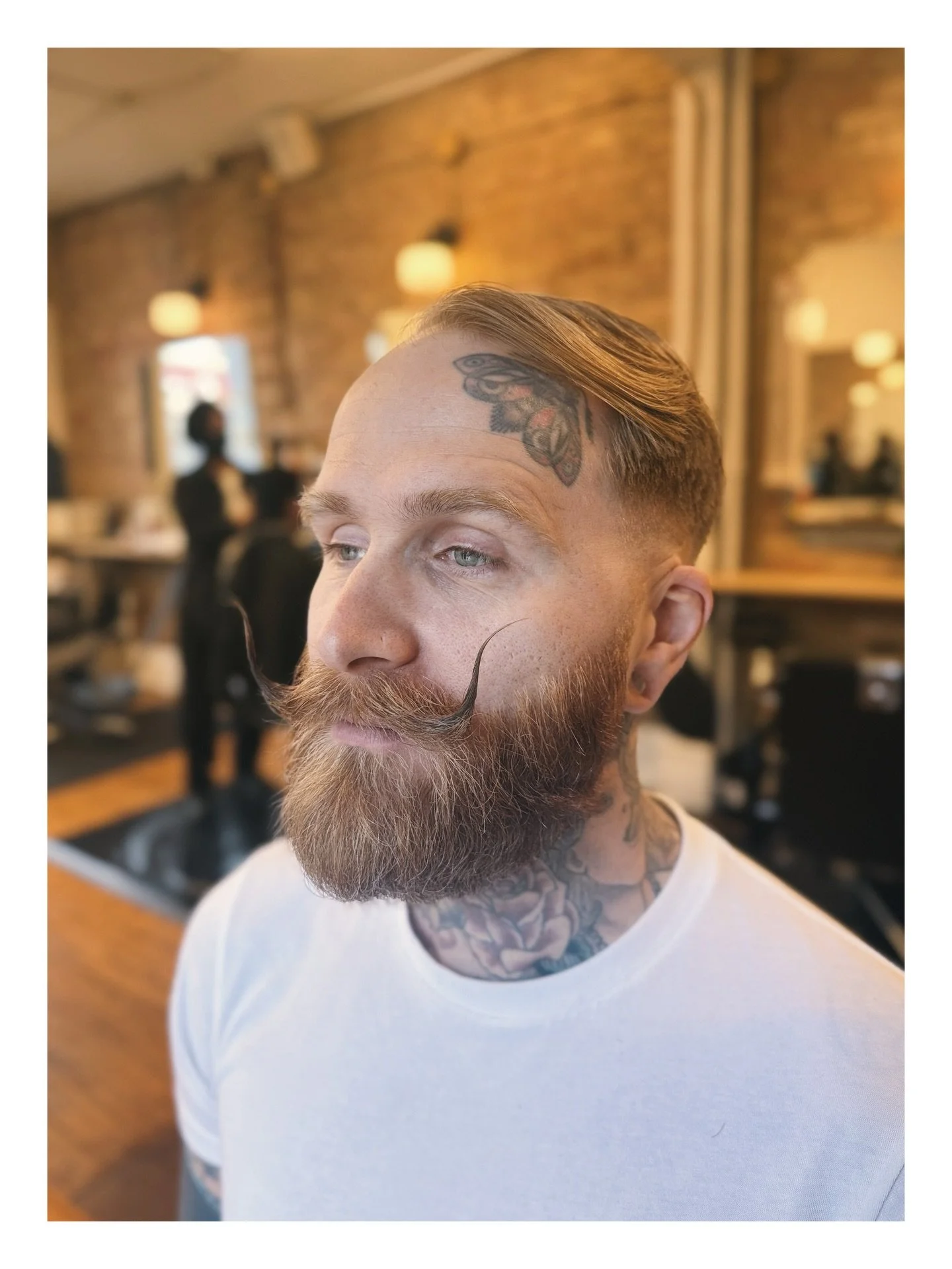 A clean side-part paired with a curled, sculpted mustache creates this distinguished look. It took Kev about 8 months to grow and we sculpted it throughout to finally achieve the final shape. &nbsp;

Here&rsquo;s what makes it work so well:
1. keeps 