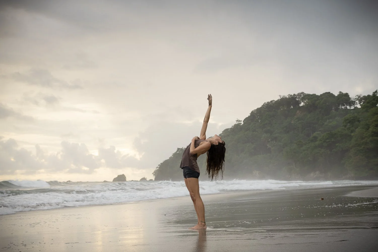 Yoga practice on the beach reaching up to the sky
