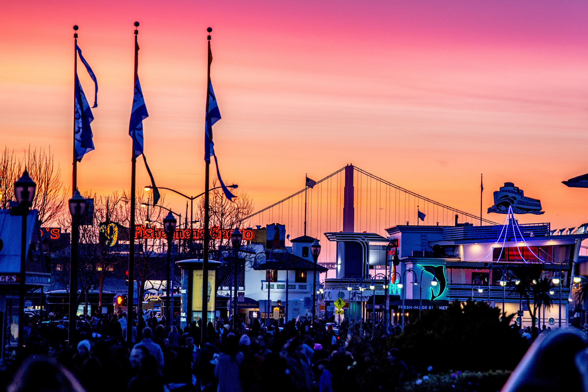 Golden gate bridge behind boardwalk businesses at dusk