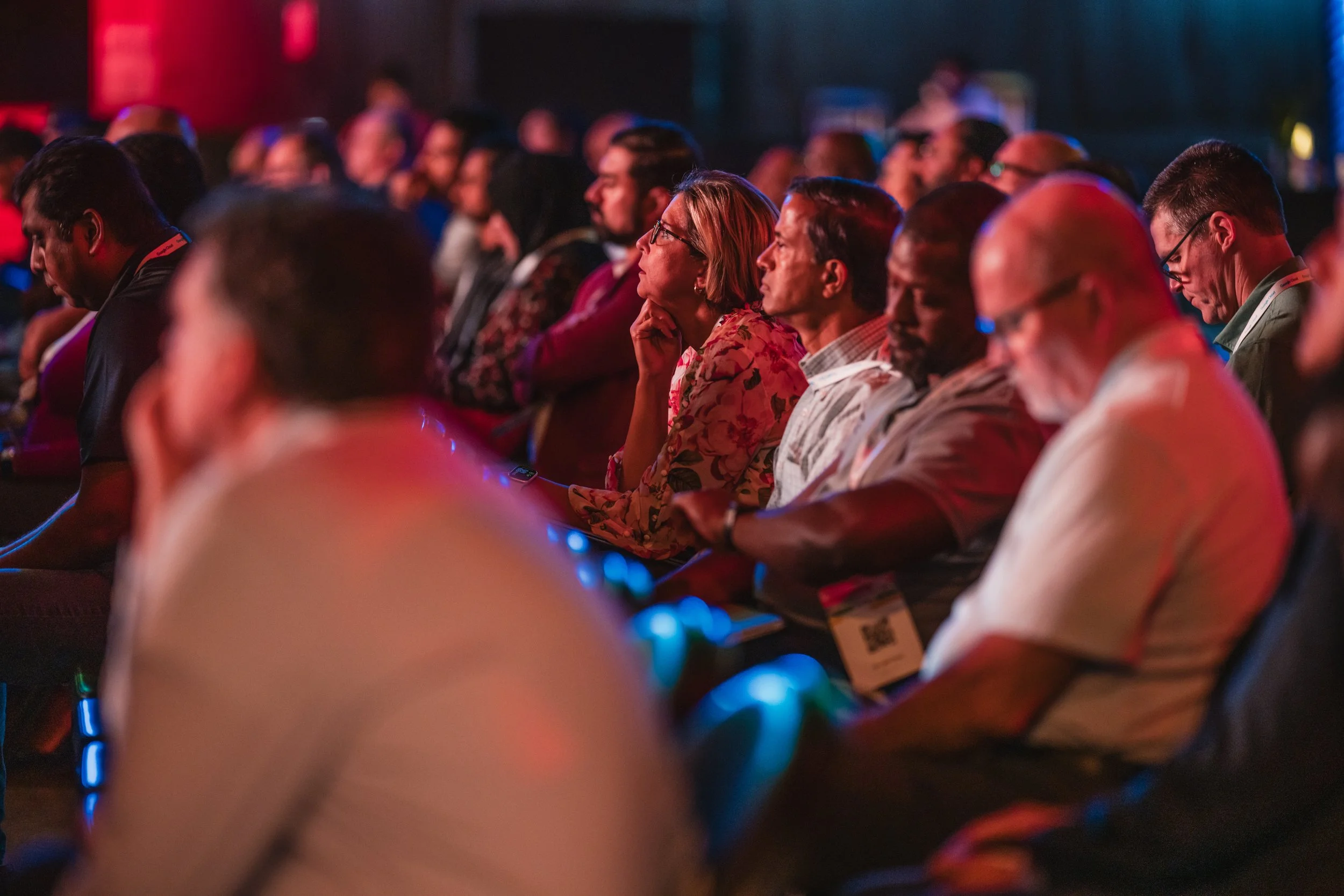 Audience sitting in a darkened auditorium, attentively listening at a conference or seminar.
