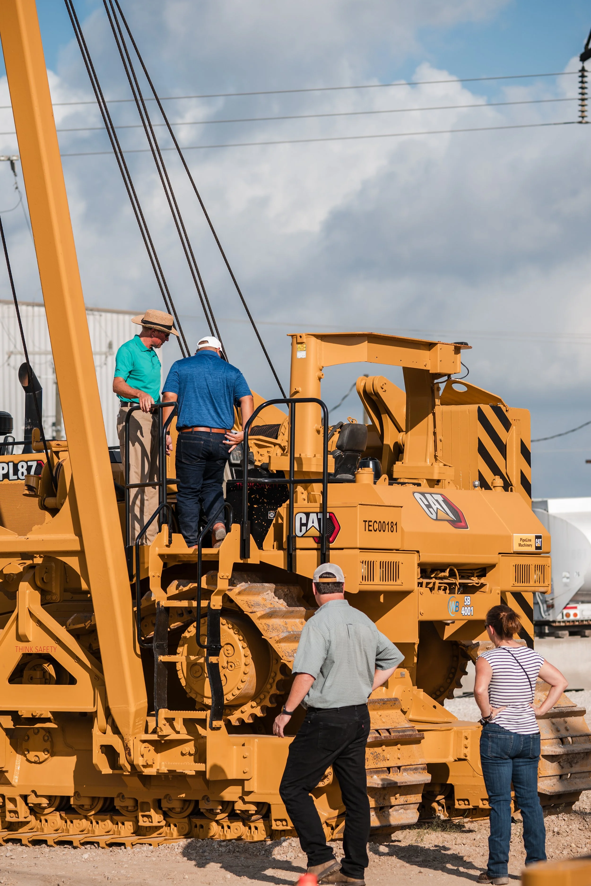 Group of people examining a large yellow Caterpillar bulldozer during a construction equipment demonstration.