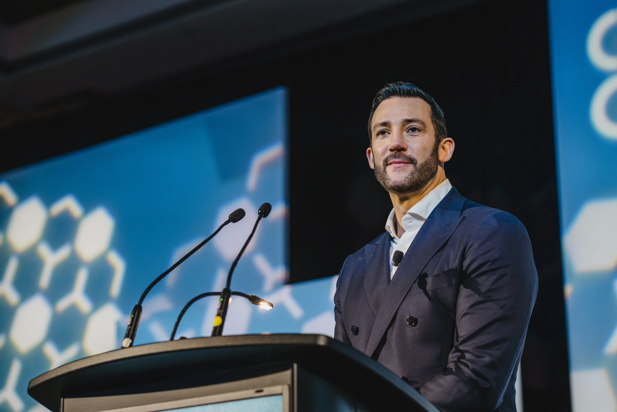 Man in a suit speaking at a podium during a conference