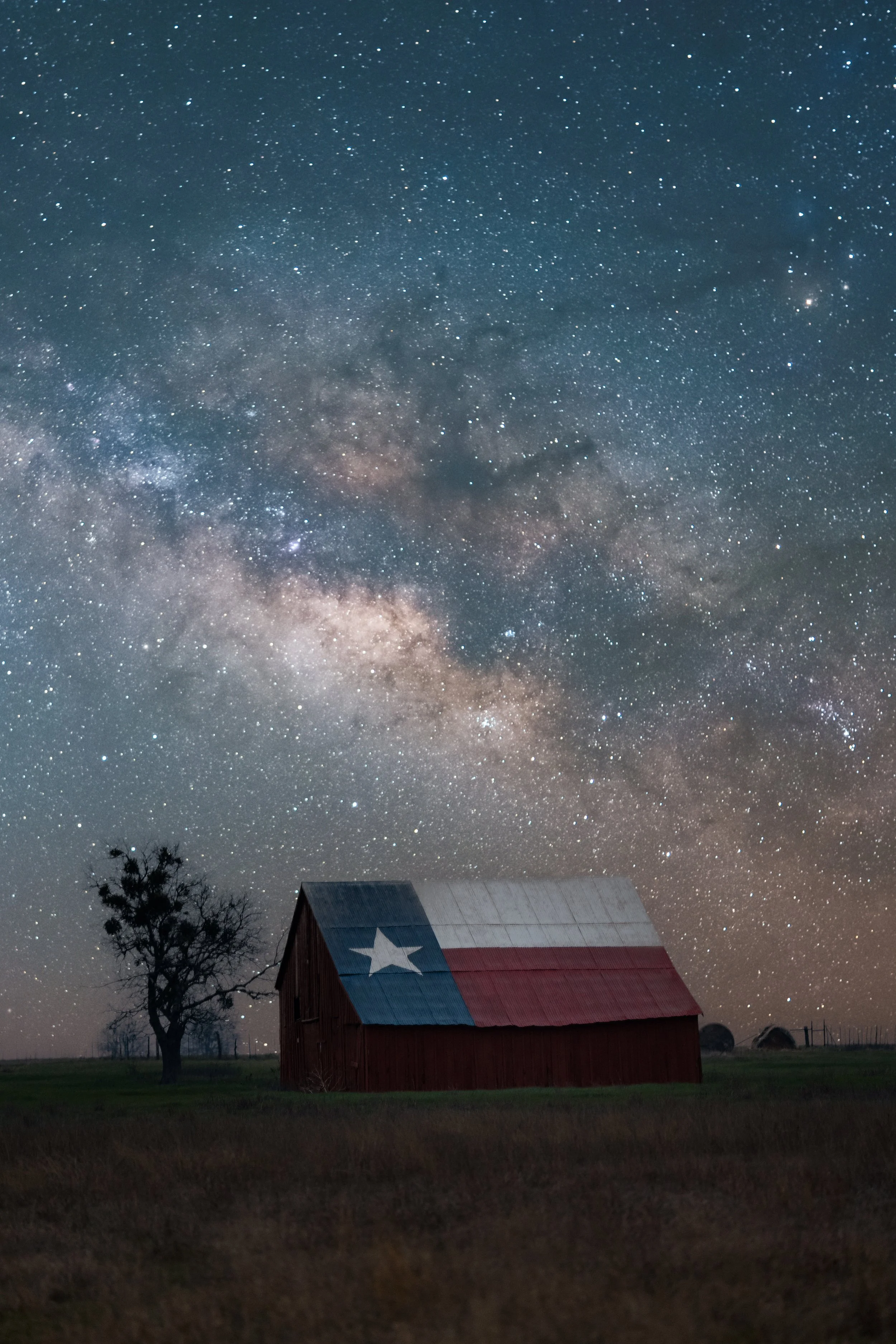 A barn painted with the Texas flag under a starry night sky showing the Milky Way galaxy.