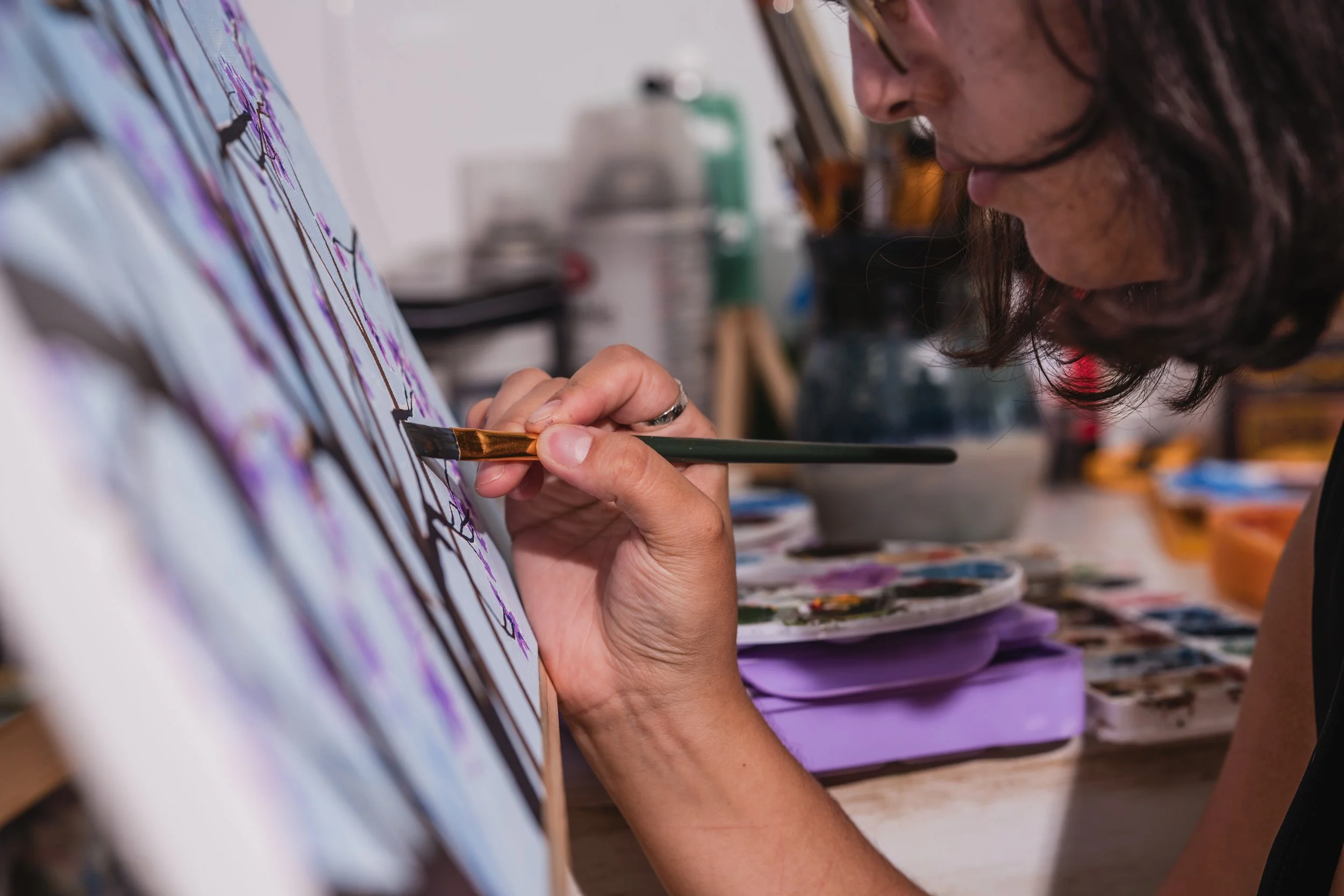 Artist painting on a canvas with watercolor paints and brushes in an art studio.
