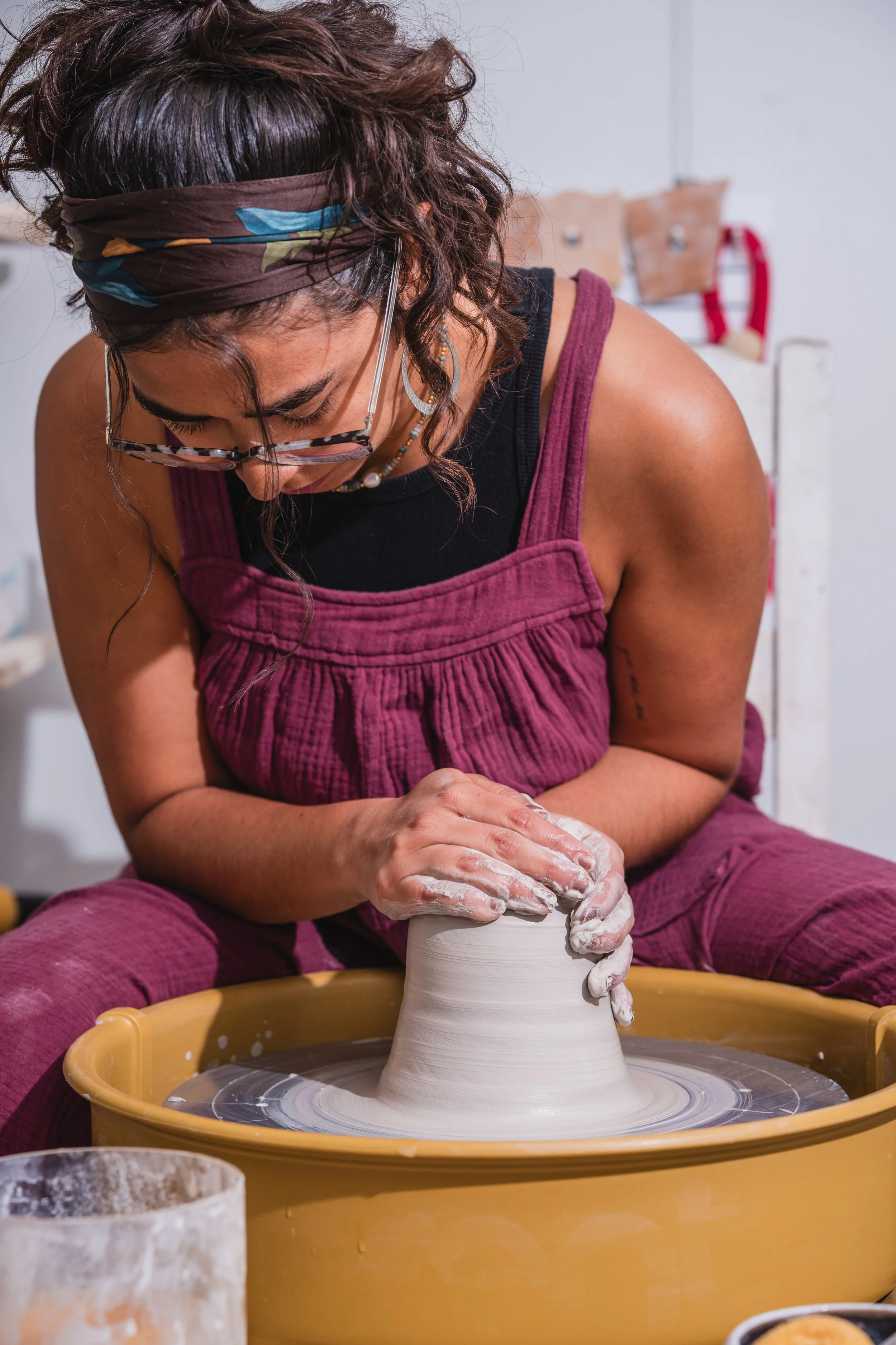 Woman shaping clay on pottery wheel in a pottery studio.