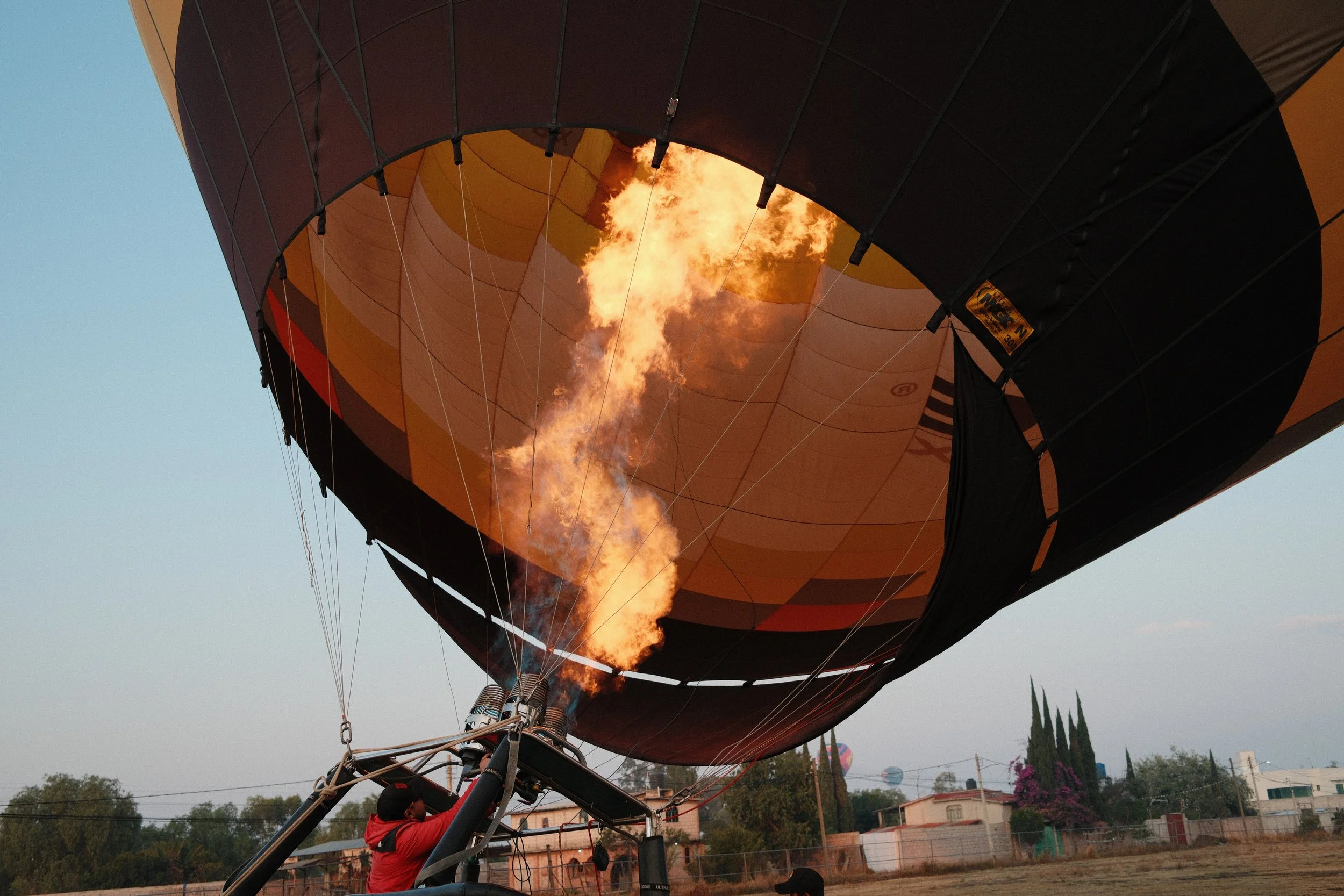 Hot air balloon with a visible flame inside, inflating during ascent process.