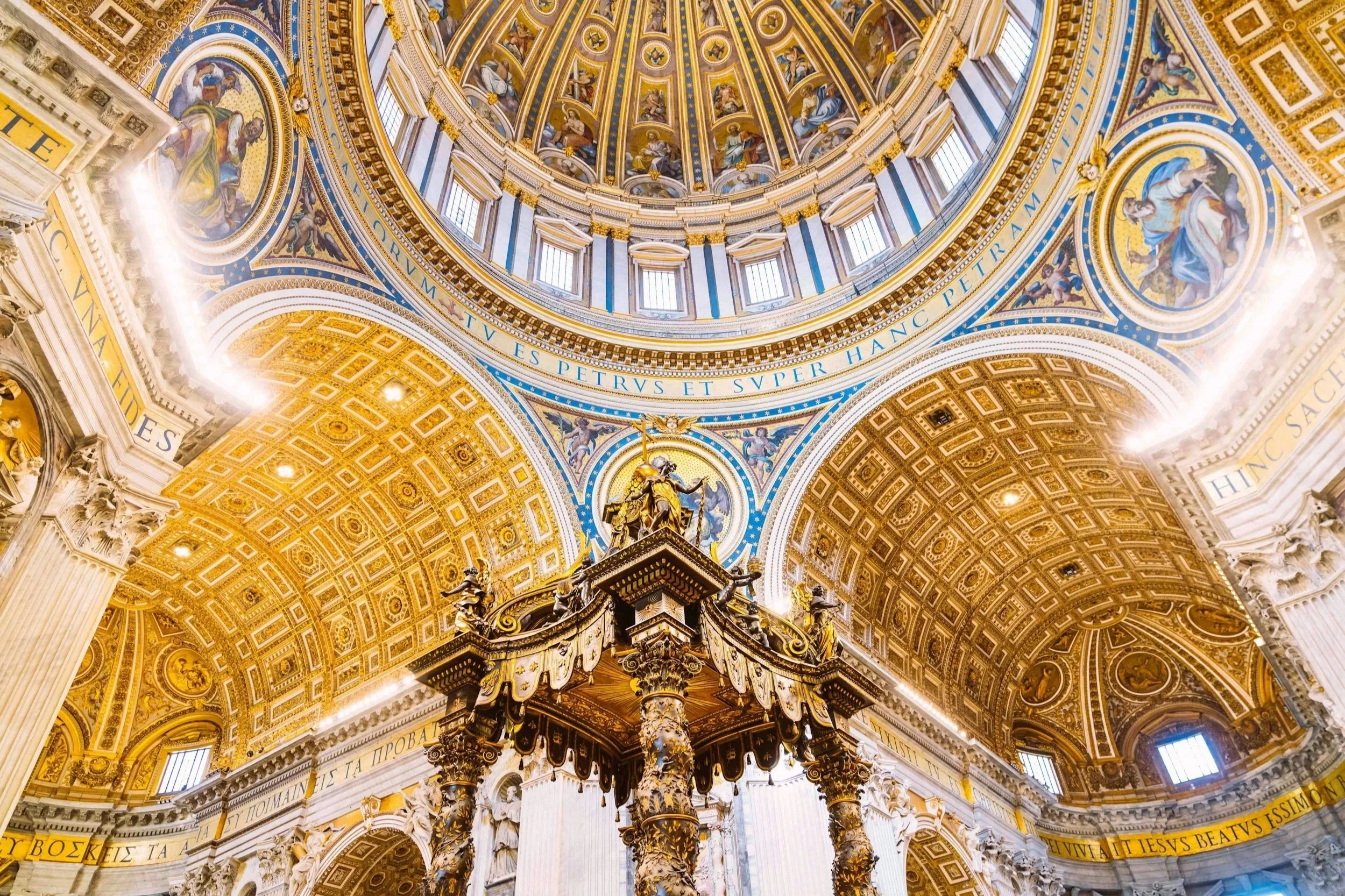 Interior of St. Peter's Basilica showing Bernini's Baldachin beneath the main ornate golden dome in Vatican City.
