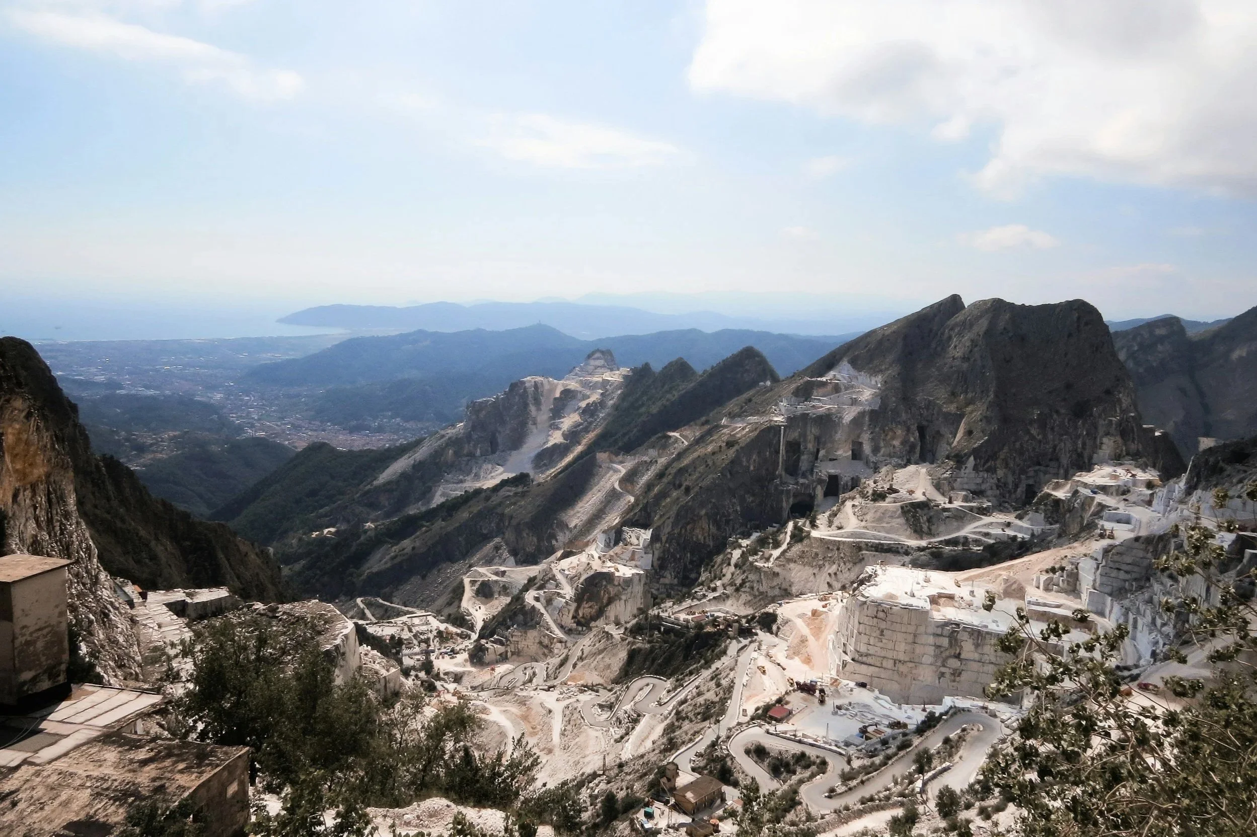 Panoramic view of white Carrara marble quarries carved into steep mountainsides in the Apuan Alps, Tuscany.