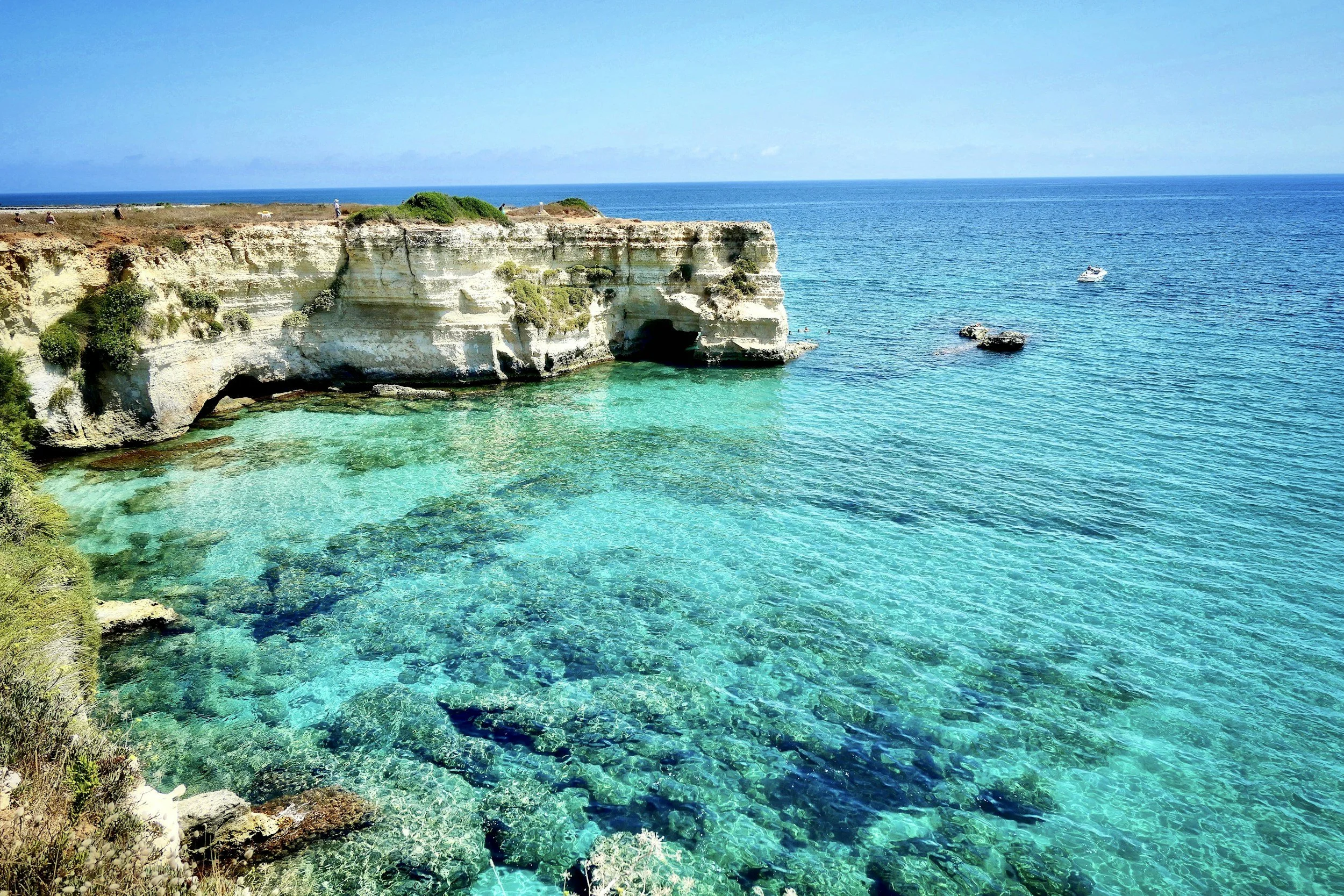 Towering white limestone cliffs and sea stacks surrounding crystal-clear turquoise waters along the coastal cliffs of Torre Sant'Andrea in Salento, Puglia, Italy.