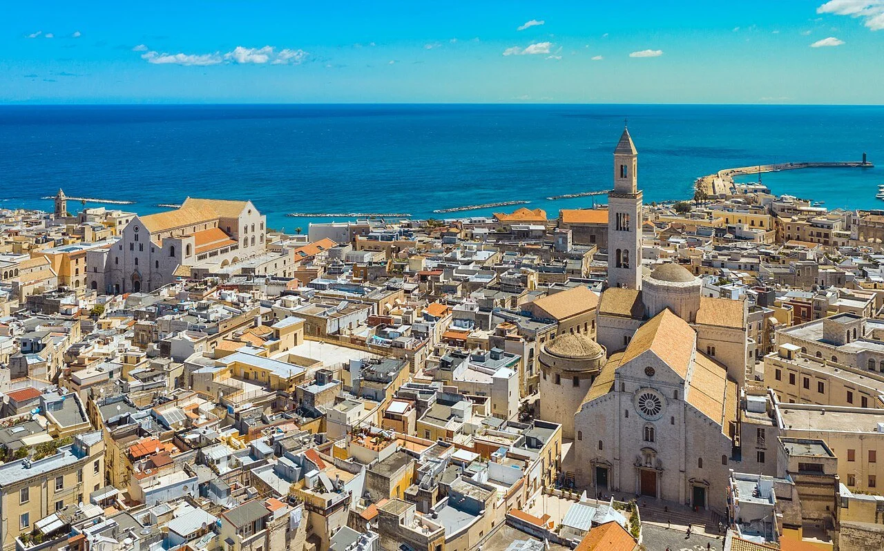 Aerial view of Bari Vecchia old town featuring the Bari Cathedral (Cattedrale di San Sabino) and Basilica di San Nicola overlooking the deep blue Adriatic Sea in Puglia, Italy.