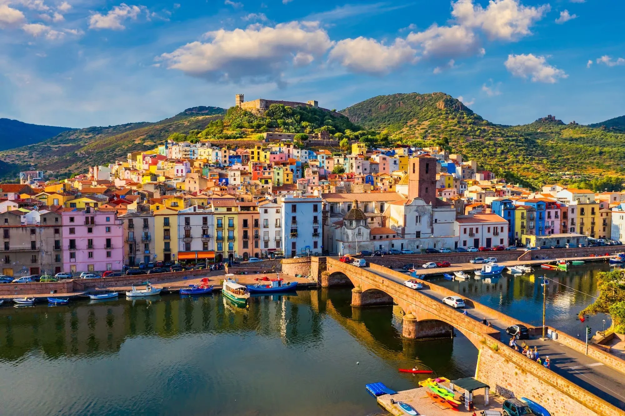 Colorful pastel-painted houses of Bosa clustered along the River Temo under the hilltop Malaspina Serravalle Castle in Sardinia, Italy.