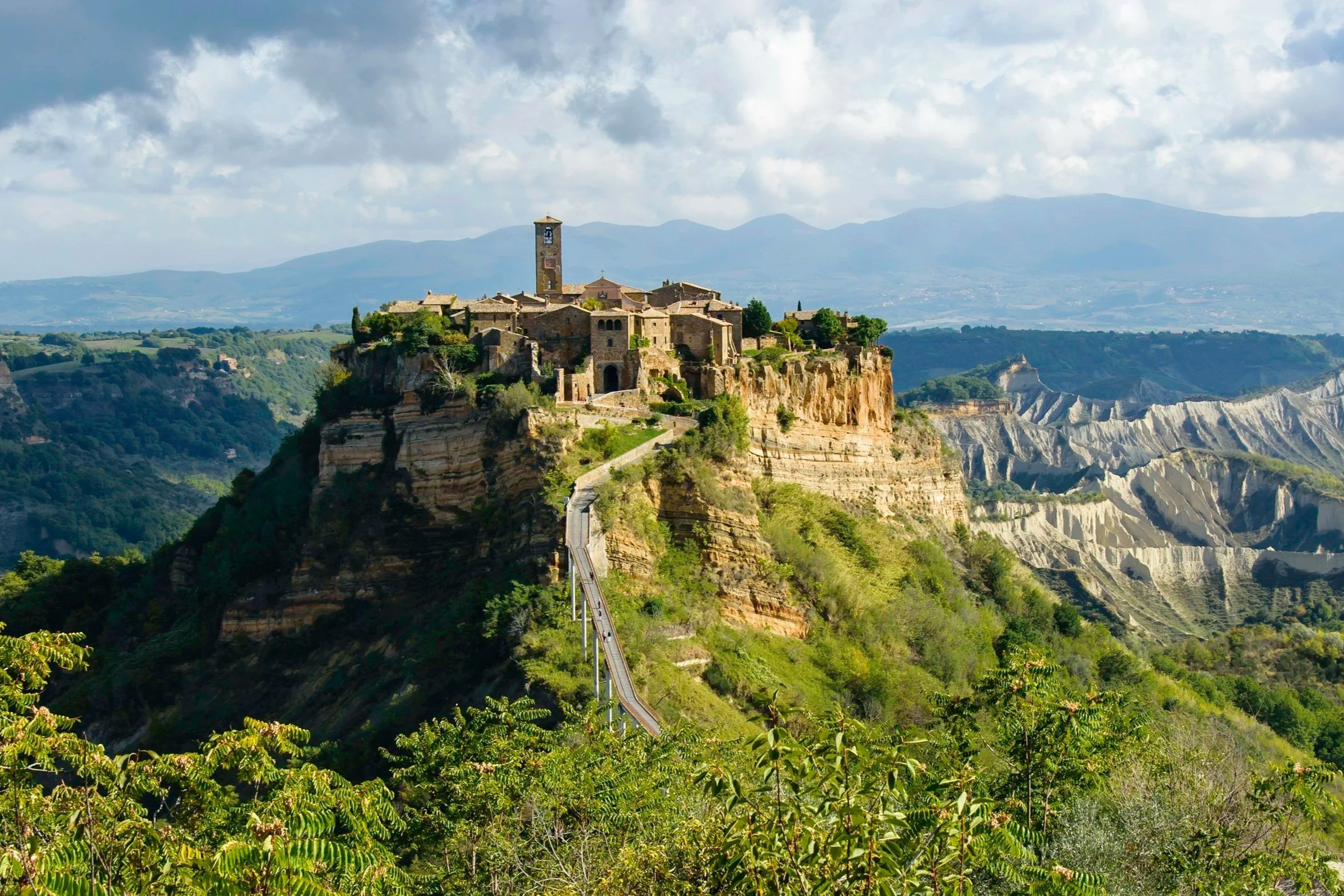 Pedestrian bridge leading up to the historic hilltop village of Civita di Bagnoregio surrounded by clay badlands"