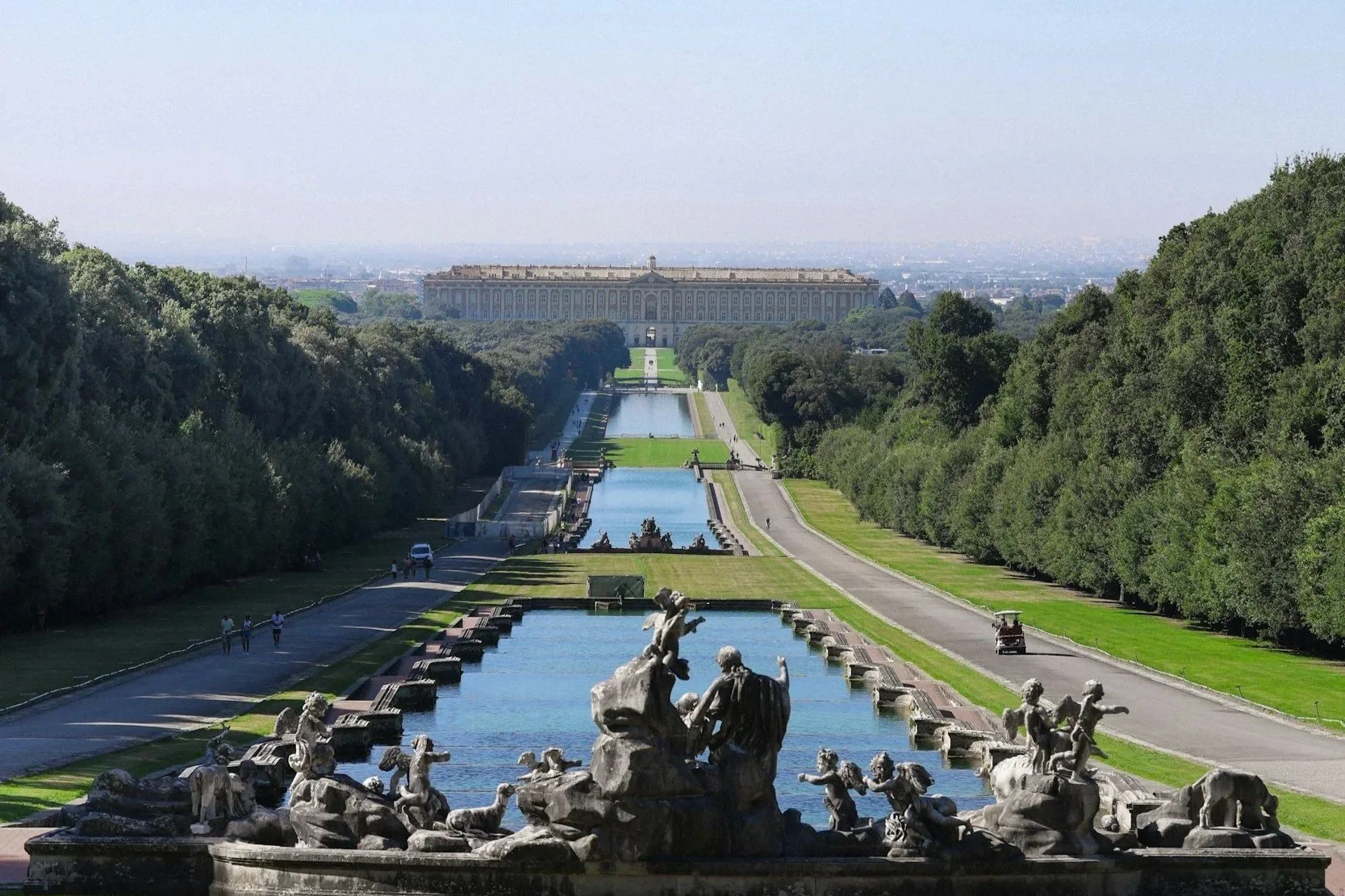 High-angle view of the Grand Cascade fountains, gardens, and distant Royal Palace of Caserta in Italy.