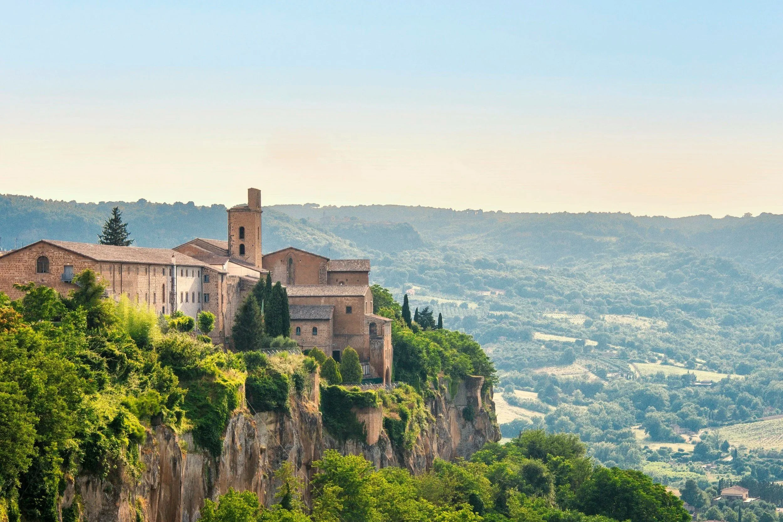 Accurately describes the image for screen readers while naturally targeting keywords like medieval town, cliffside, green valleys, and Umbria Italy.