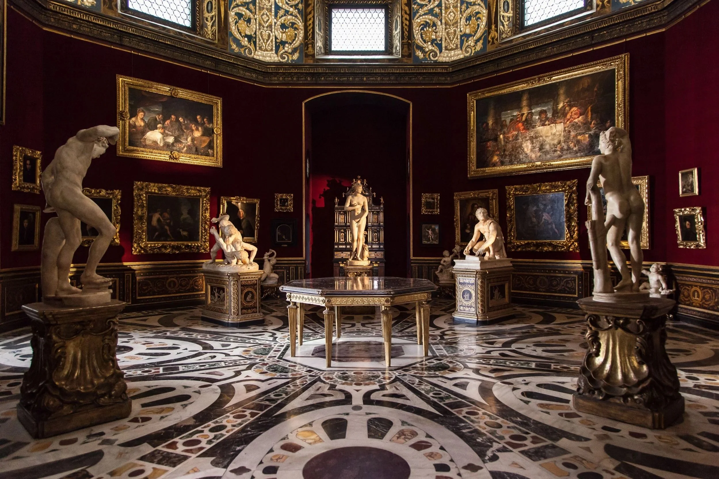 The octagonal Tribuna room inside the Uffizi Gallery in Florence with classical sculptures, oil paintings, and ornate marble floor