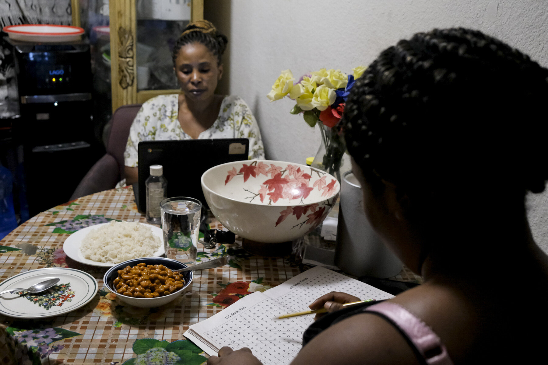  USA, San Diego, CA, October 26, 2020. Over dinner, Edina Shabani, 20, works through an U.S. Fish crossword puzzle while her mother, Shabani attends a school district meeting for ESL parents.&nbsp; The meetings aim to foster feedback on distance lear