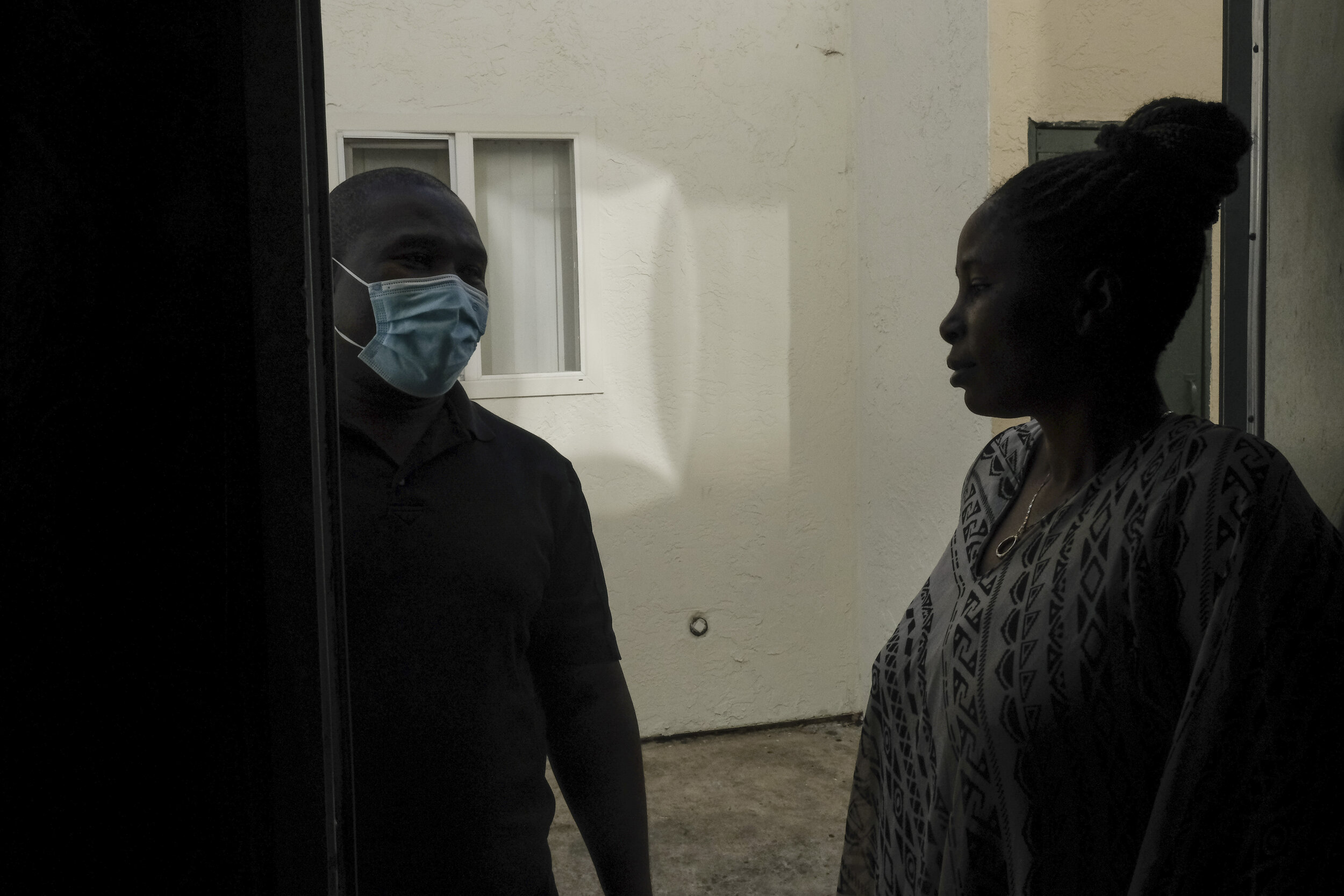  USA, San Diego, CA, December 1, 2020. Nyamangah talks with Shabani in her doorway after dropping off school supplies and diapers. Nyamangah is a community organizer for Parent Student Resident Organization (PSRO), where he met Shabani.&nbsp; PSRO ac