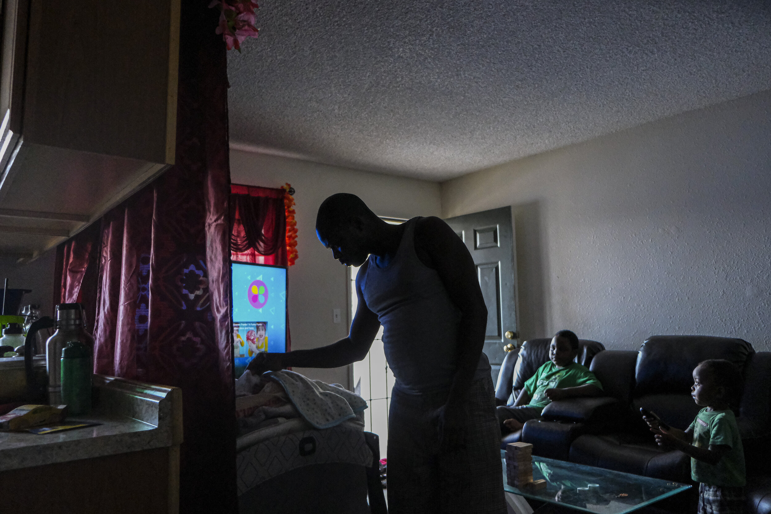  USA, San Diego, CA, October 27, 2020. After returning from work, Desire Ndayisenga, 40, checks on his newborn daughter. His wife Merie Sindayigaya, 38, says she’s thankful for Ndayisenga’s job after losing her own because of COVID-19. After fleeing 