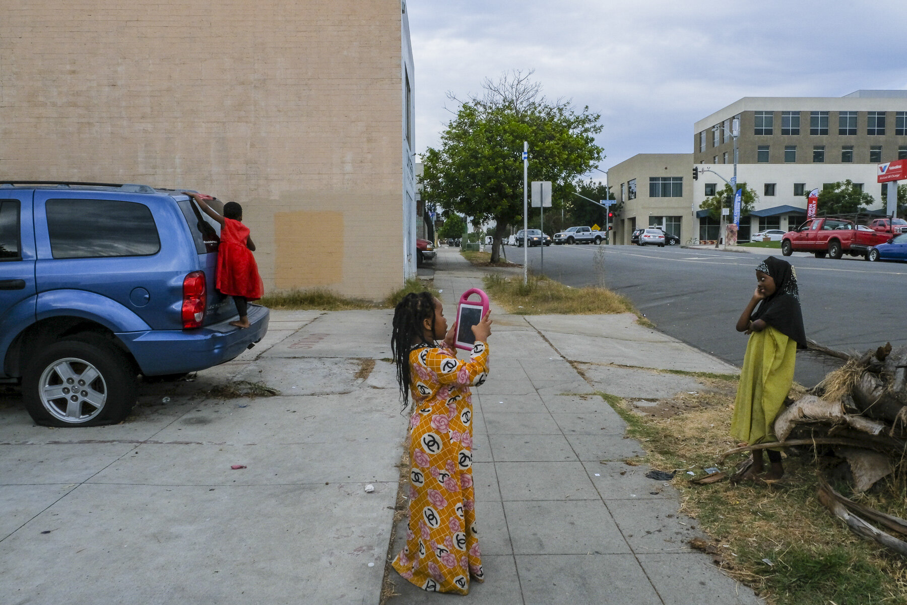  USA, San Diego, CA, November 5, 2020. Sadiya, 7, and her cousins Nuriya, 7, and Safiya, 5, take and pose for photographs after class. In the midst of her indigenous literature Zoom class, Musa notices the girls outside and quickly calls them back in