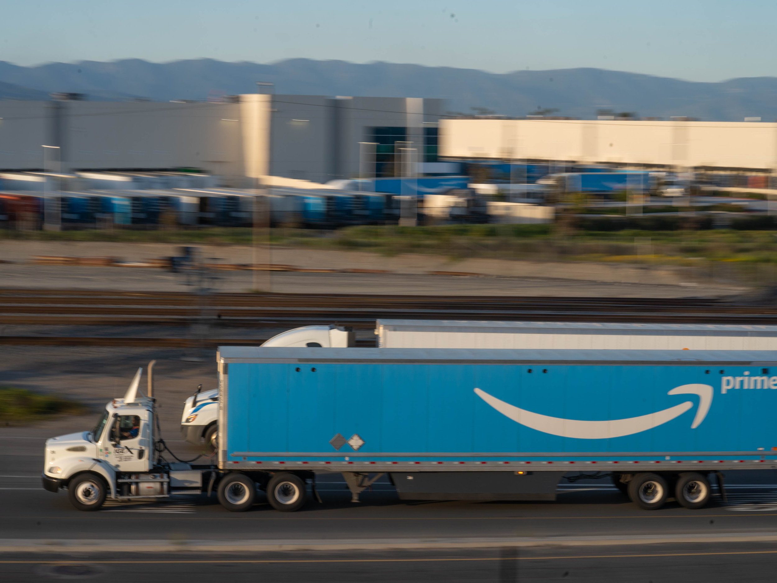  An Amazon truck edges ahead of a Walmart truck as they drive in between California State Route 60 west and Interstate 215 north in Ontario on April 4, 2023. Once known for its dairy farming, Ontario will soon be home to the largest Amazon warehouse 
