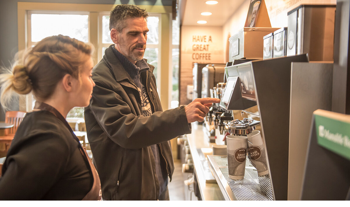 A male customer standing beside a brand ambassador making his coffee selection at the brand activation