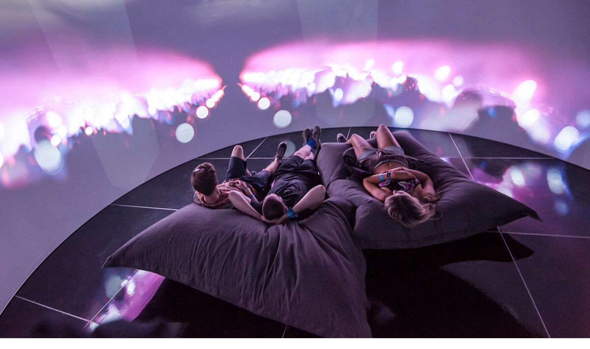 3 people laying on pillows in a 360-degree theatre that included two projectors with mapping overlay functions