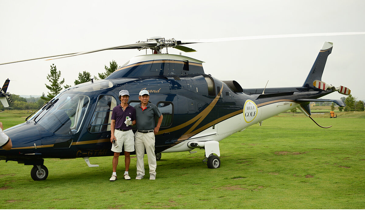 Two golfing men standing infront of helicopter waiting to be transported to another golf course to continue their round
