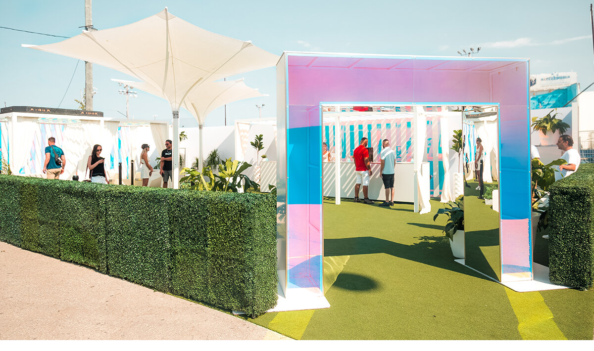 Entrance area into the Vype brand activation at Cabana Pool Bar in downtown Toronto. Multicoloured Iridescence archway at front connected to long hedge walls. 