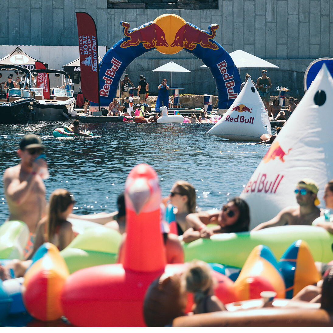 Iconic Red Bull archway located on a dock with people in floaties underneath it at brand activation. 