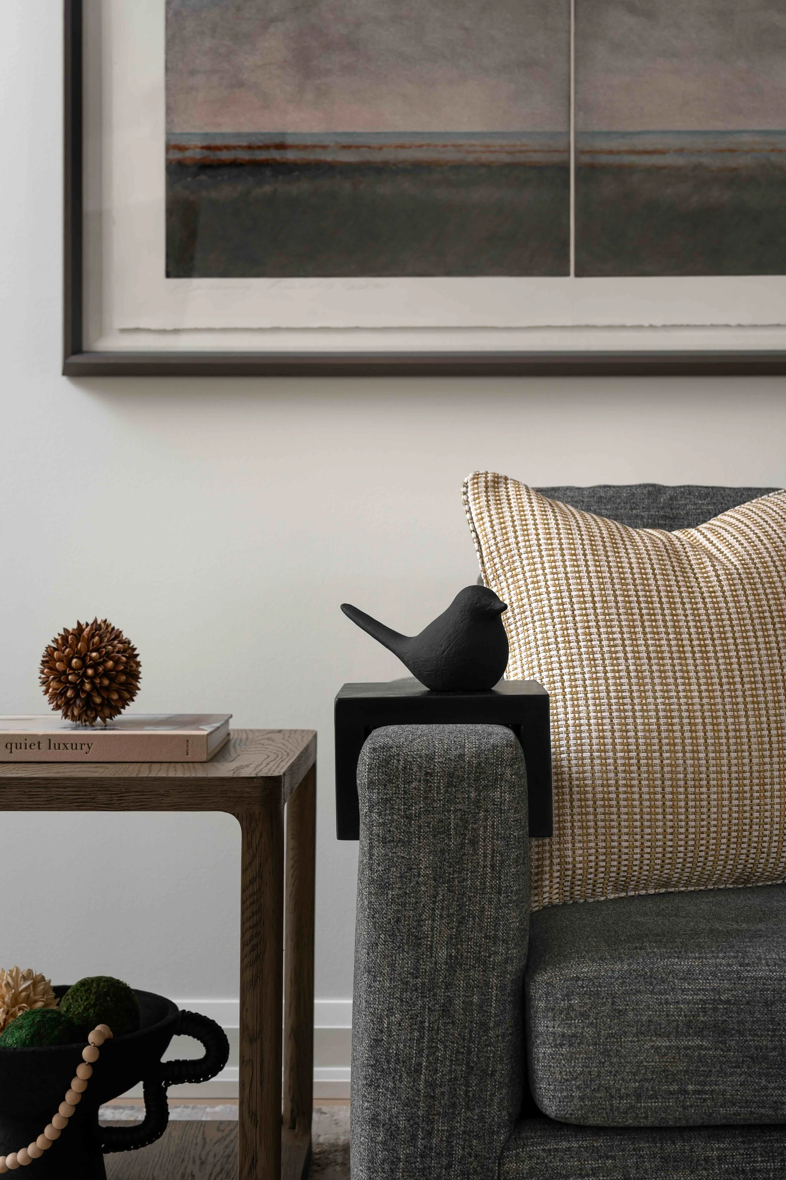 Modern living room styling detail with wood side table, sofa, and decorative accessories.