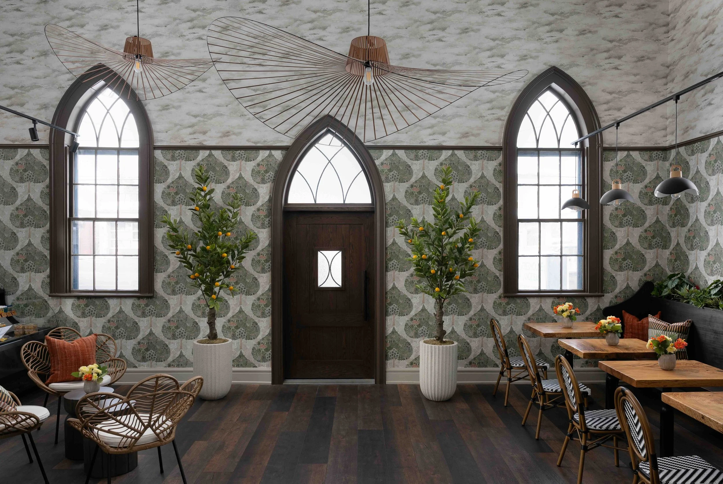 CAFE interior with arched windows, botanical wallpaper, and natural wood furniture