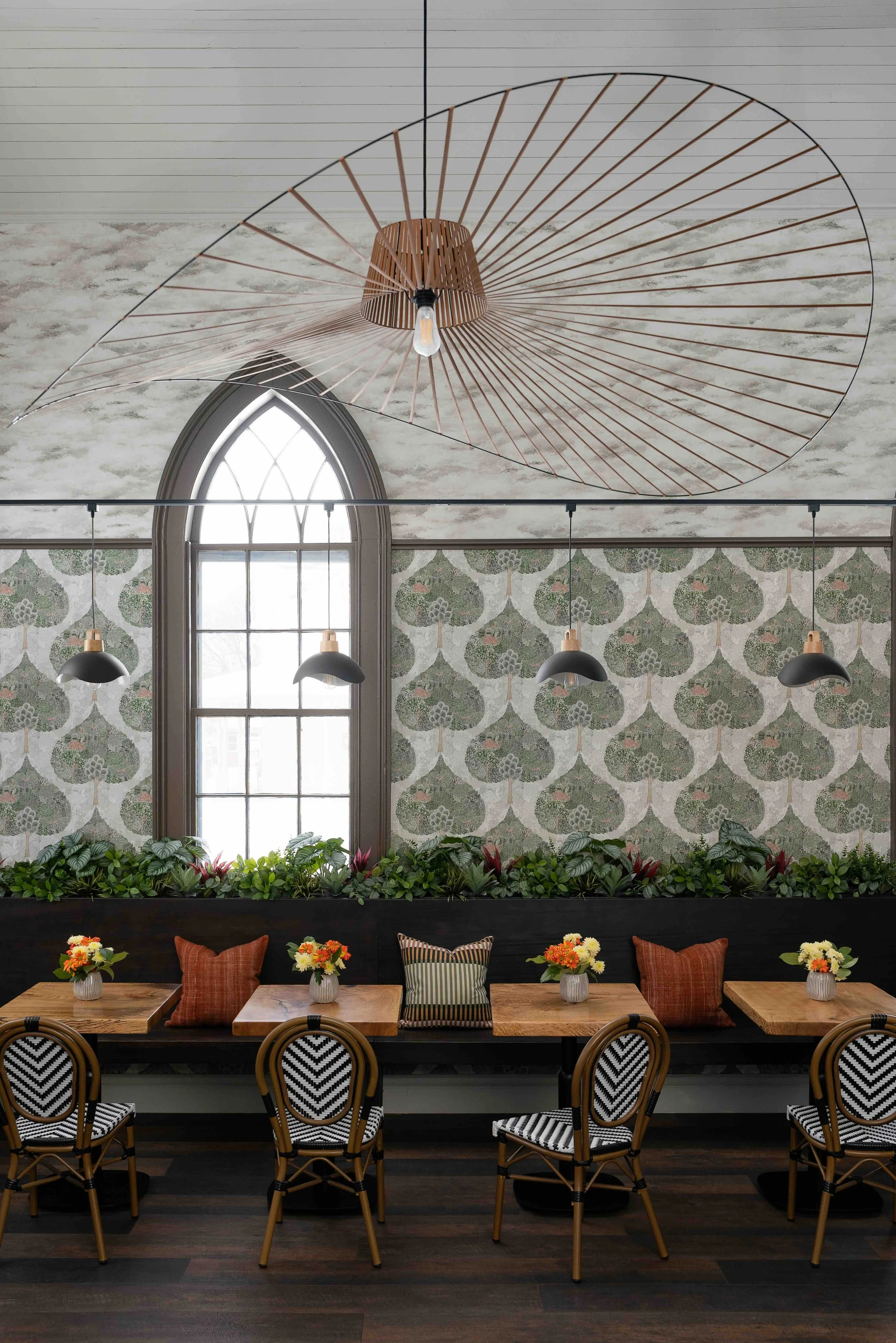 Cafe interior with arched window, botanical wallpaper, and custom seating