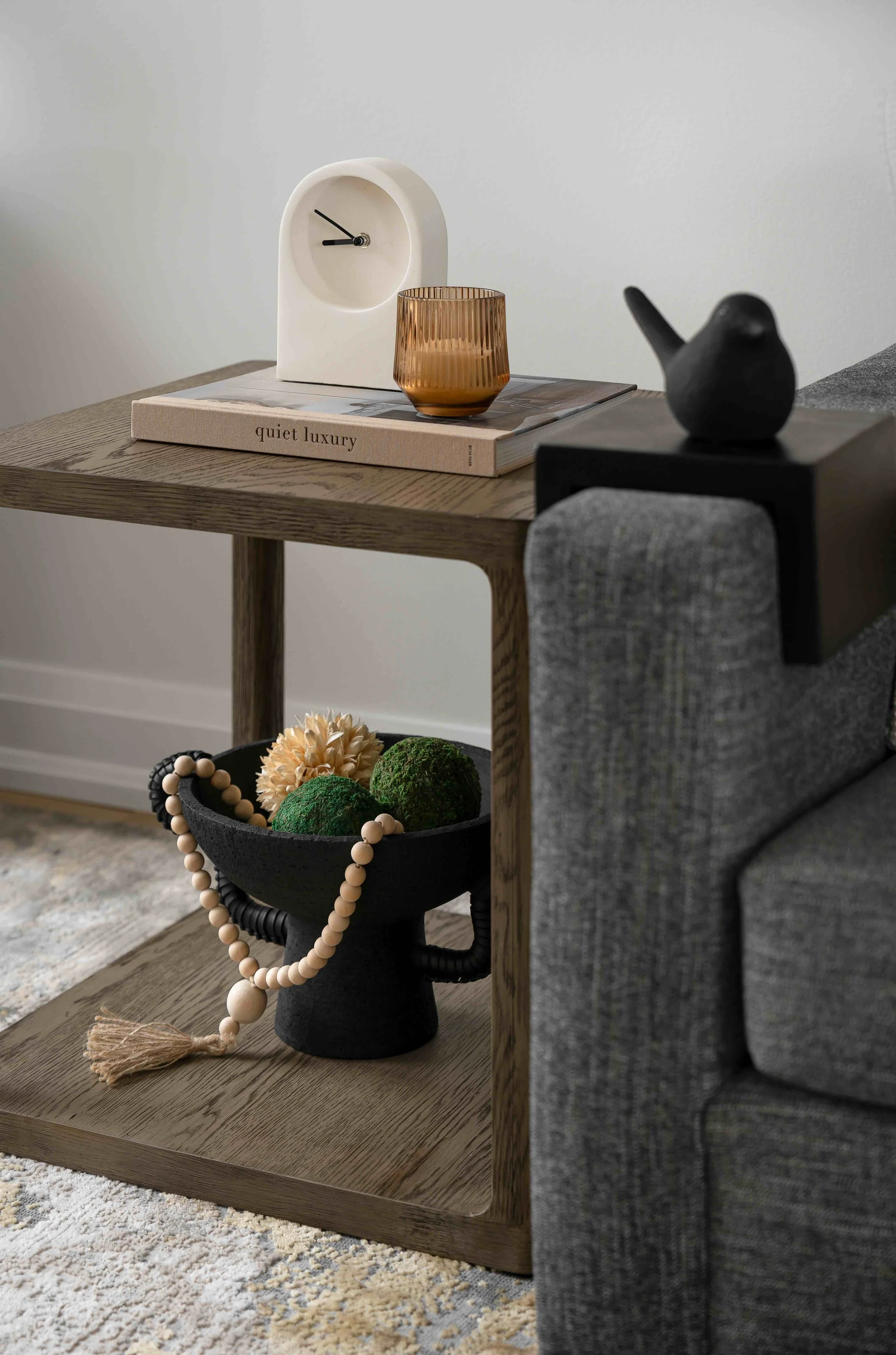 Modern living room styling detail with wood side table, sofa, and decorative accessories.