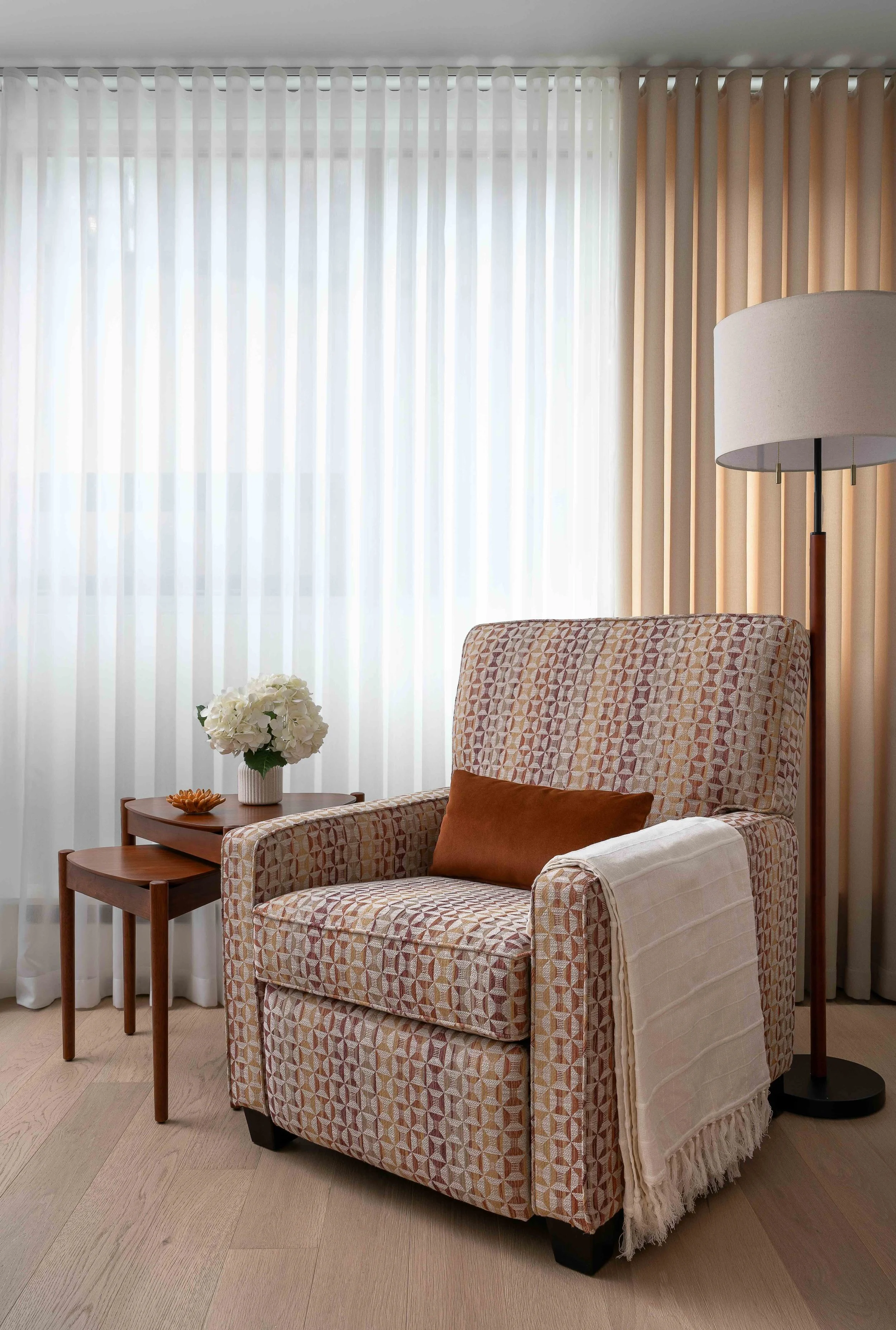 Modern bedroom reading nook with upholstered accent chair, side table, and floor lamp.
