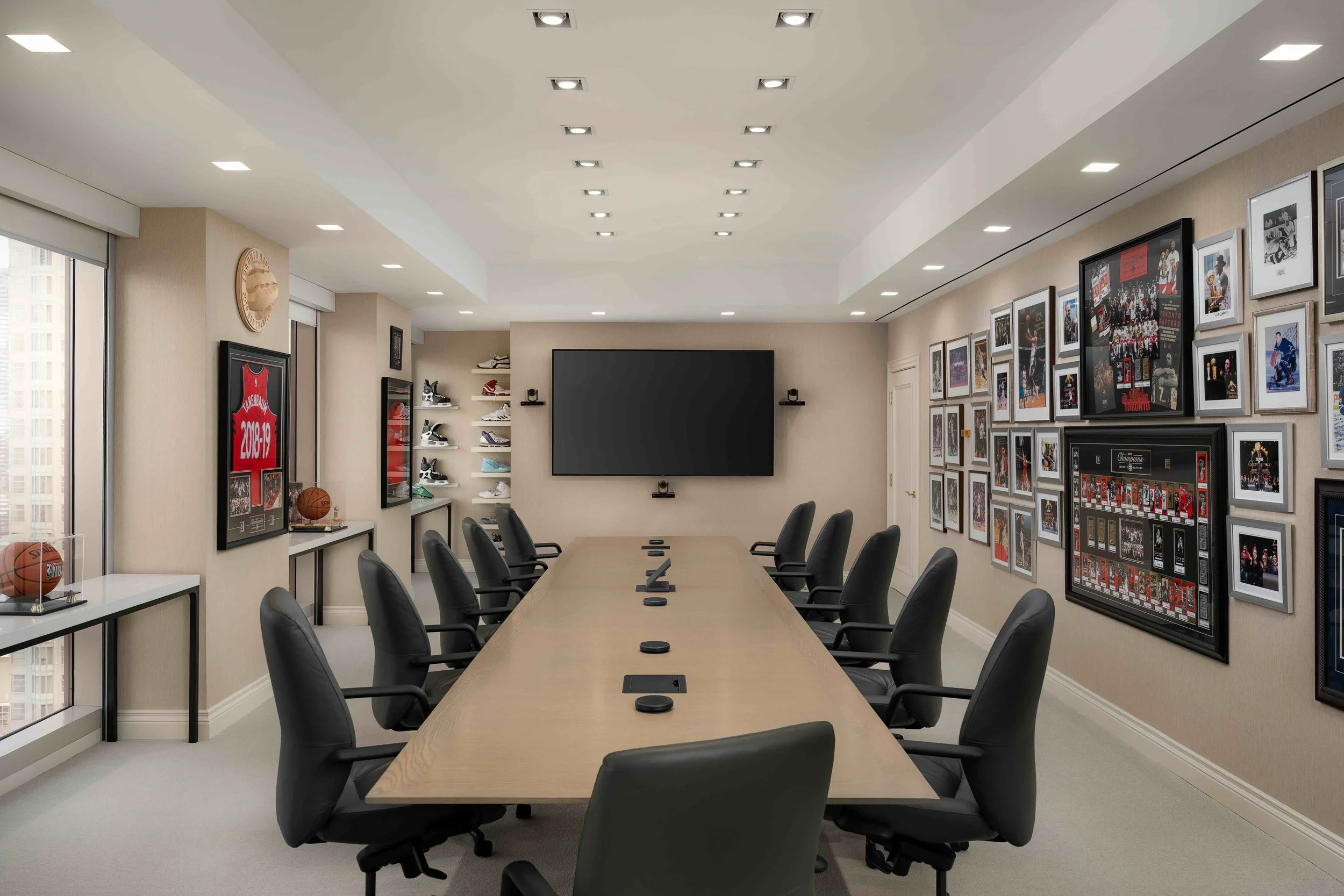 Modern office boardroom with sports memorabilia gallery wall and large conference table in a Toronto corporate office.