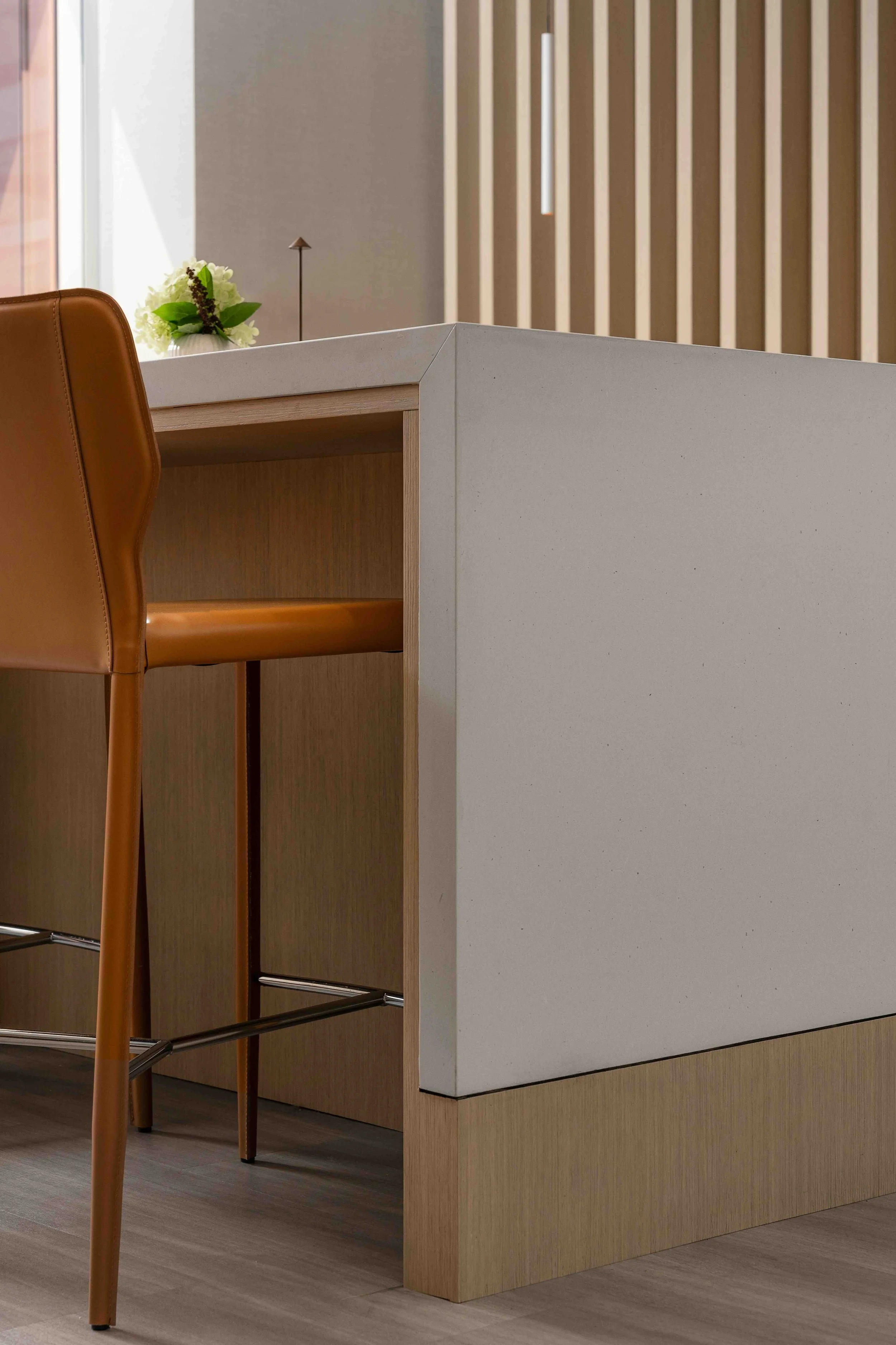 Modern office kitchen island with quartz countertop, wood base, and bar seating in a contemporary workspace.