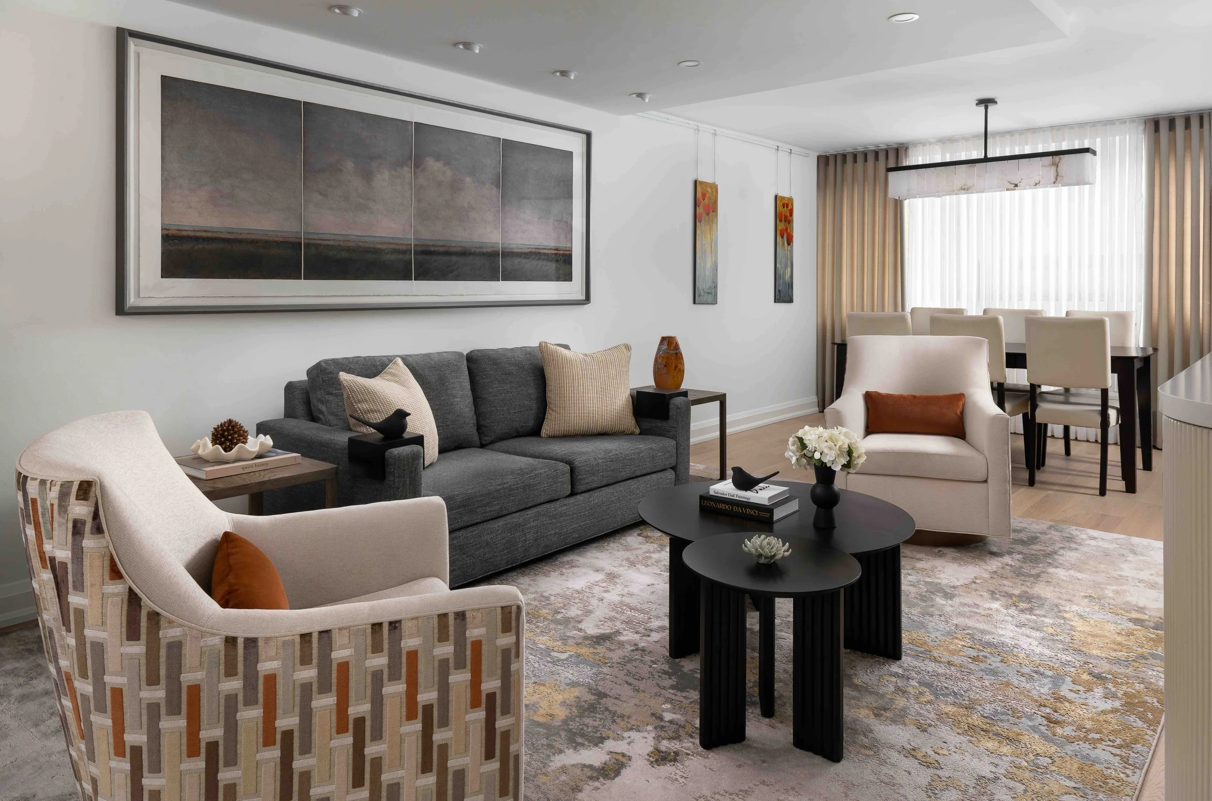 Modern condo living room interior design with neutral palette, contemporary furniture, and open dining area.