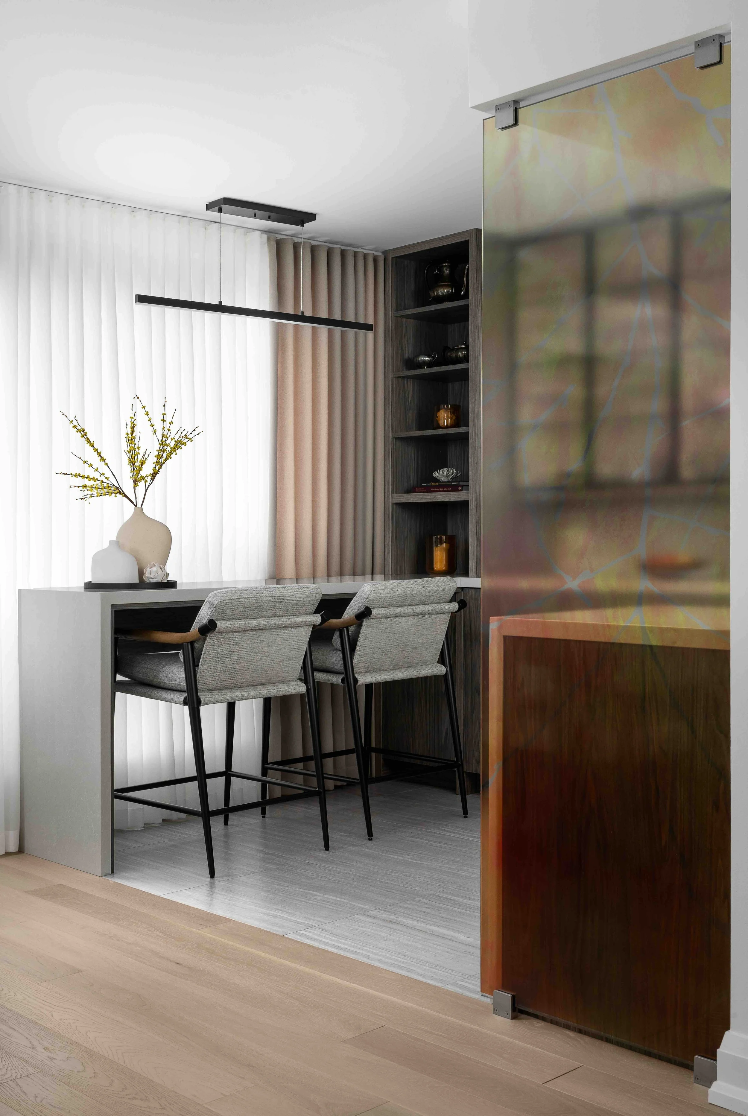 Modern condo breakfast bar with custom shelving and decorative glass partition.