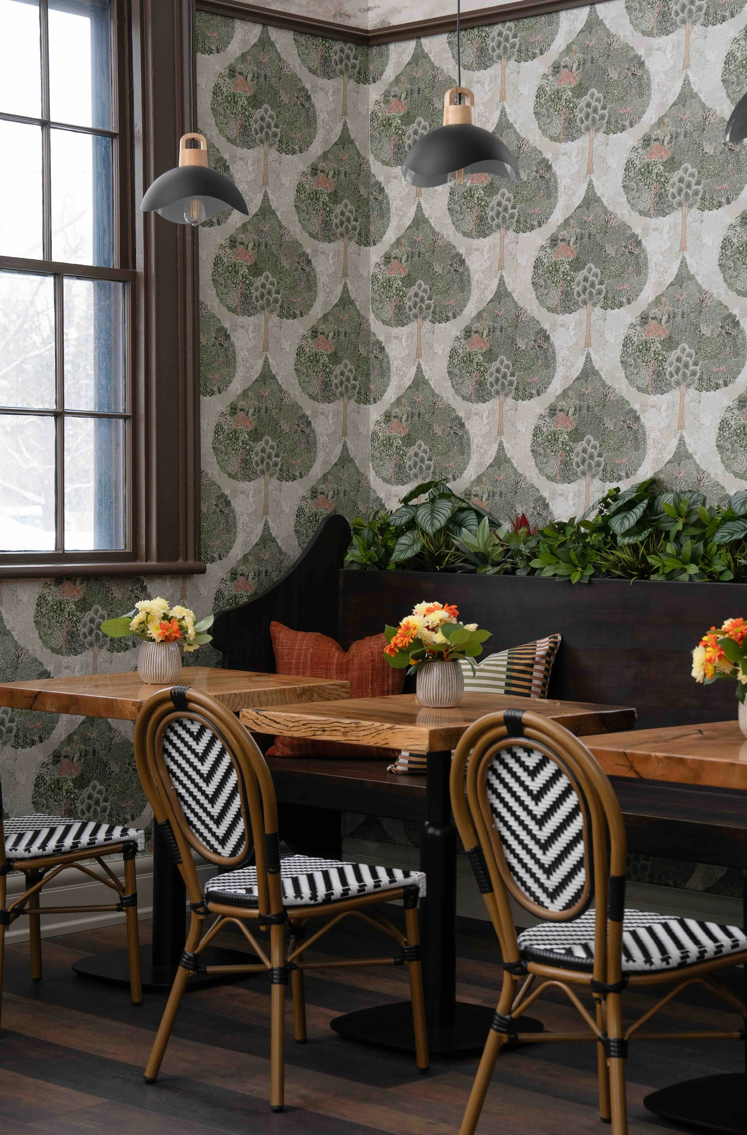 Cafe seating area with botanical wallpaper, wood tables, and bistro chairs