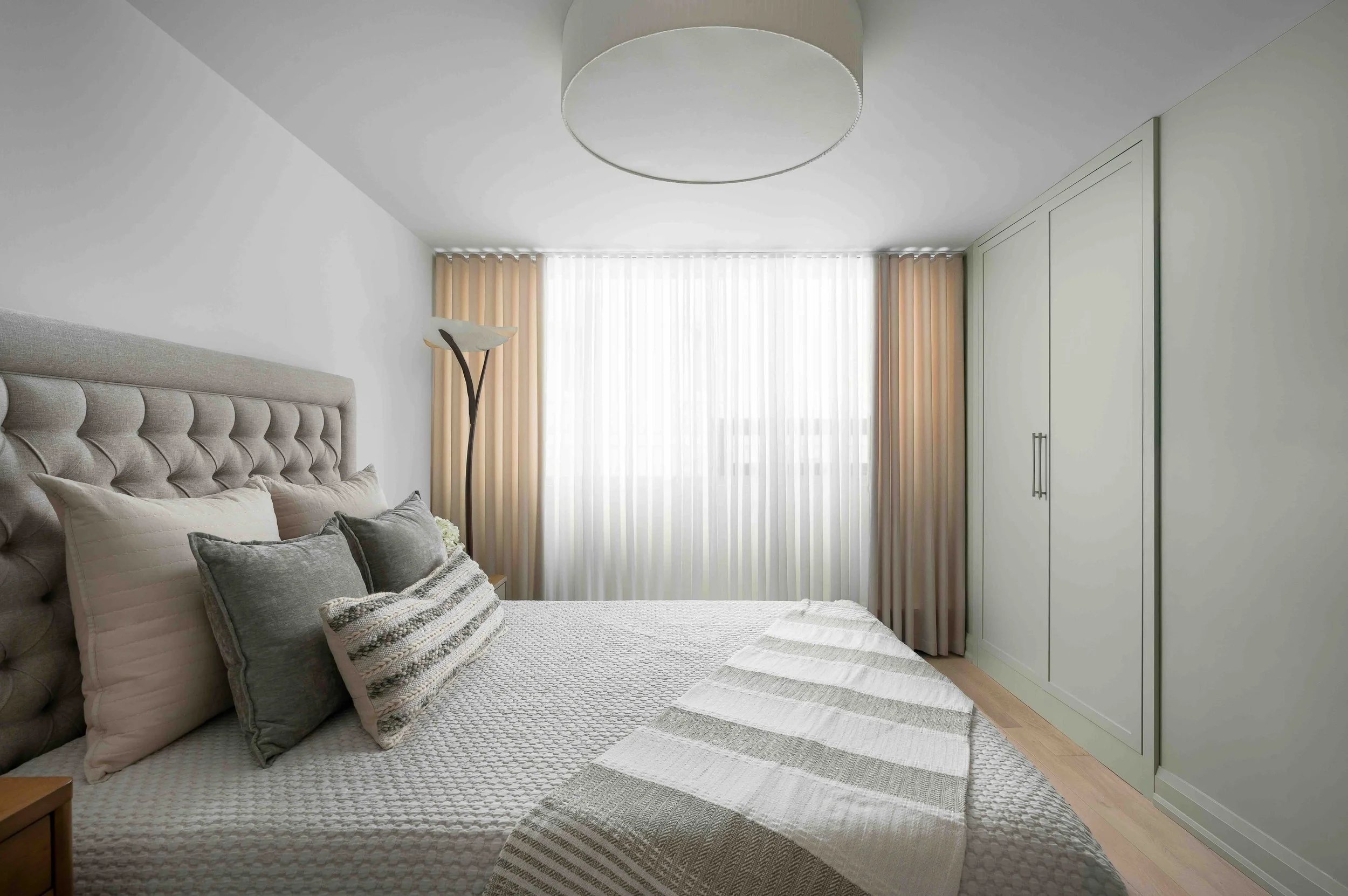 Modern condo bedroom with upholstered headboard and custom built-in wardrobe storage.