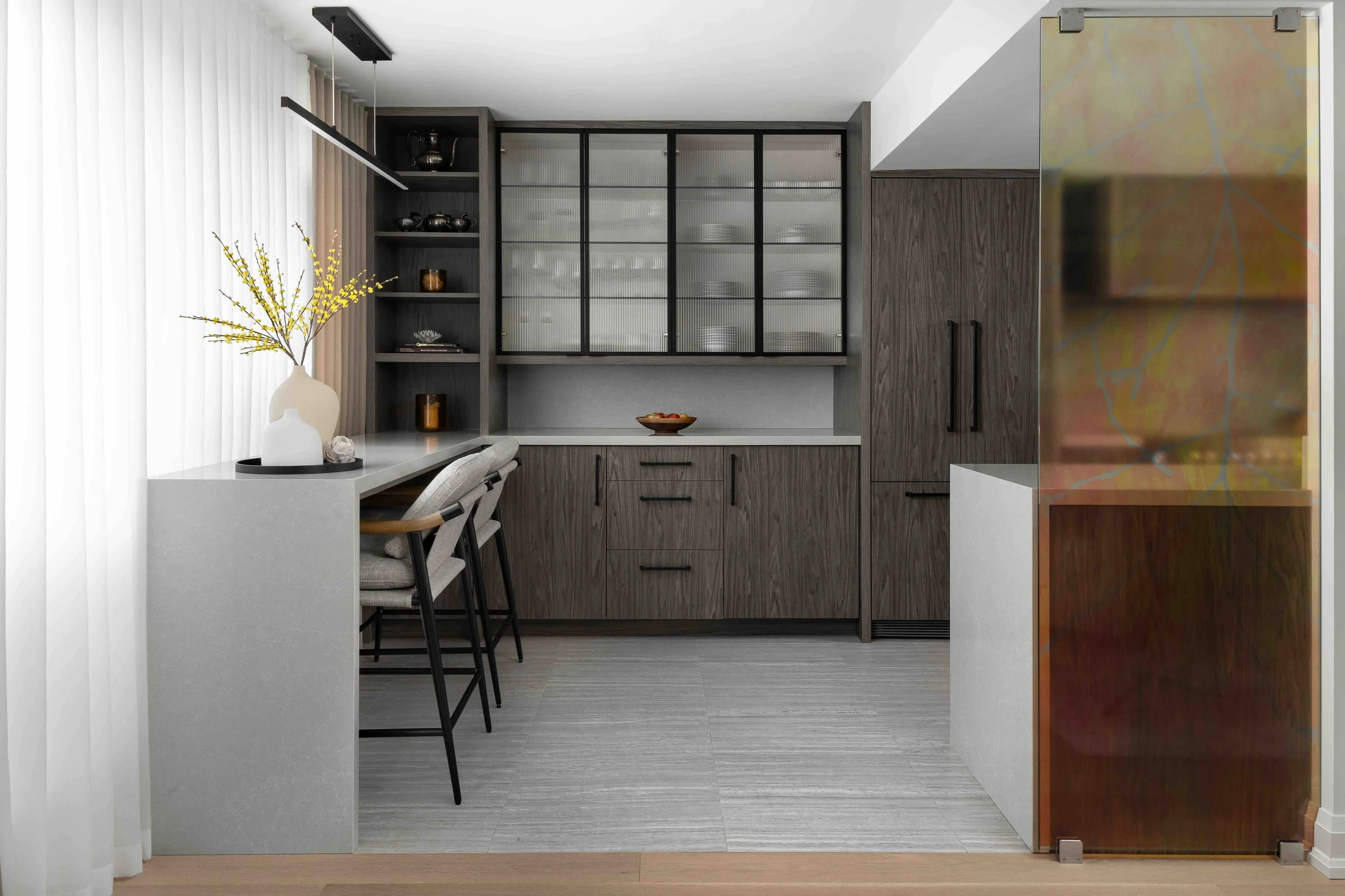 Modern condo kitchen with custom cabinetry, glass display cabinets, and integrated dining bar.