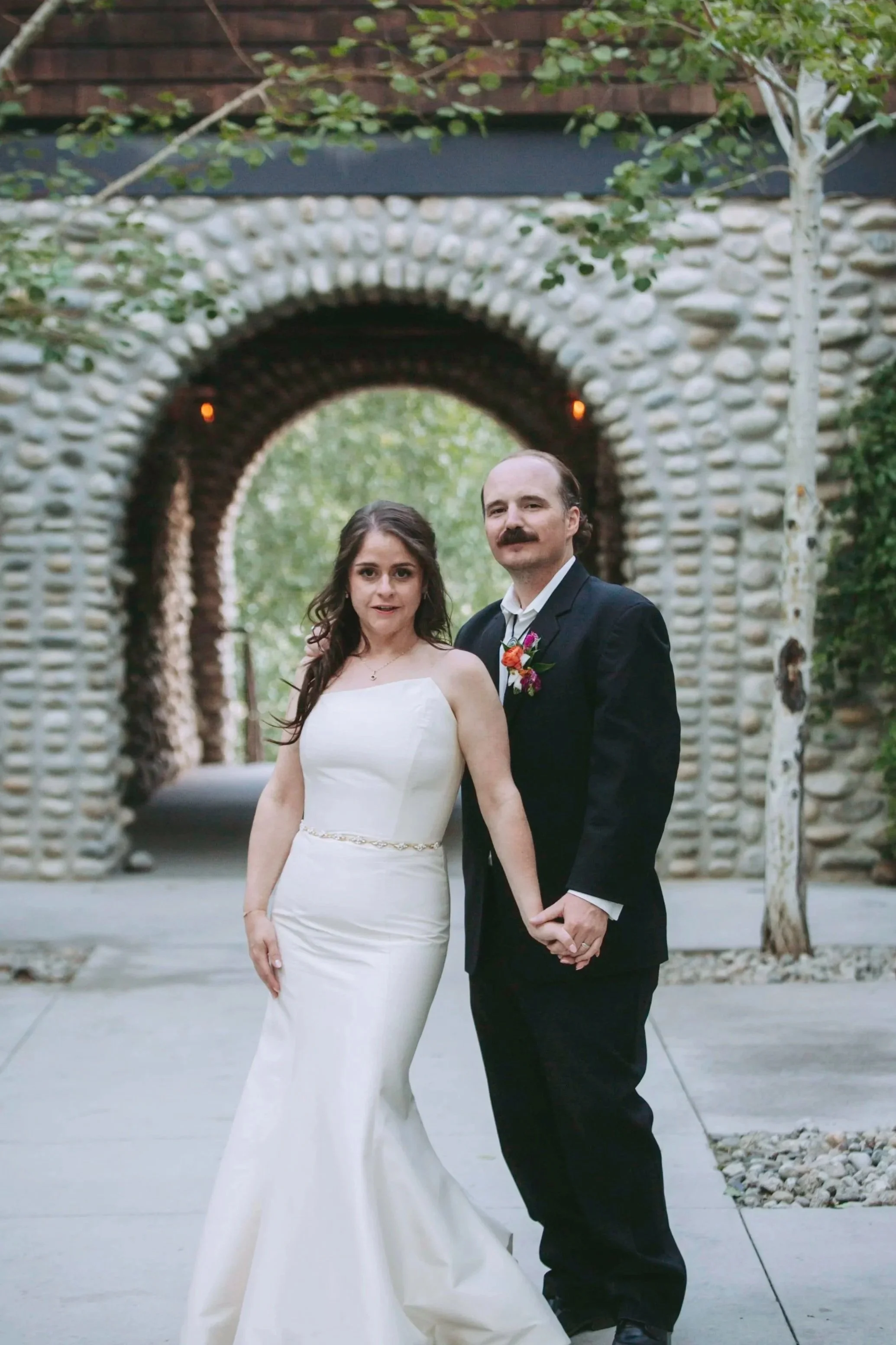  A couple poses for wedding photos in the courtyard in front of a stone fall at the Colorado wedding venue Surf Hotel in Buena Vista, Colorado.