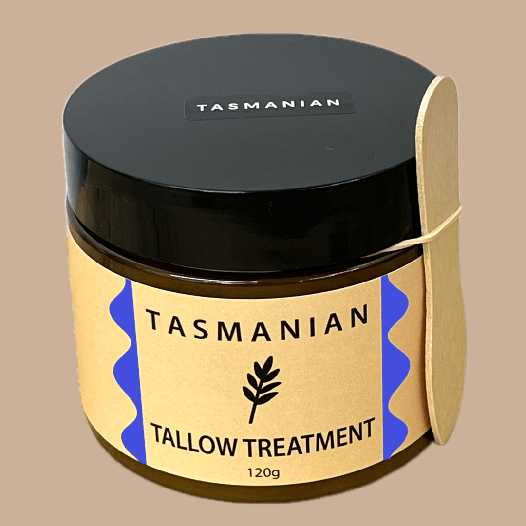 A jar of Tasmanian Tallow Treatment with a black lid, beige label with blue accents, and a black silhouette of a plant, set against a neutral background.