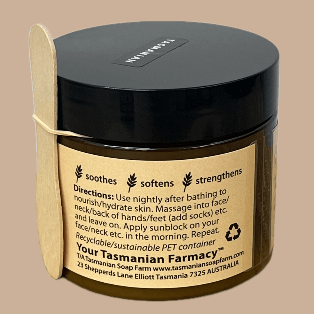 A dark brown jar with a black lid containing soap from Tasmanian Soap Farm. The label states it soothes, softens, and strengthens skin, with usage directions, website, and address in Tasmania, Australia.